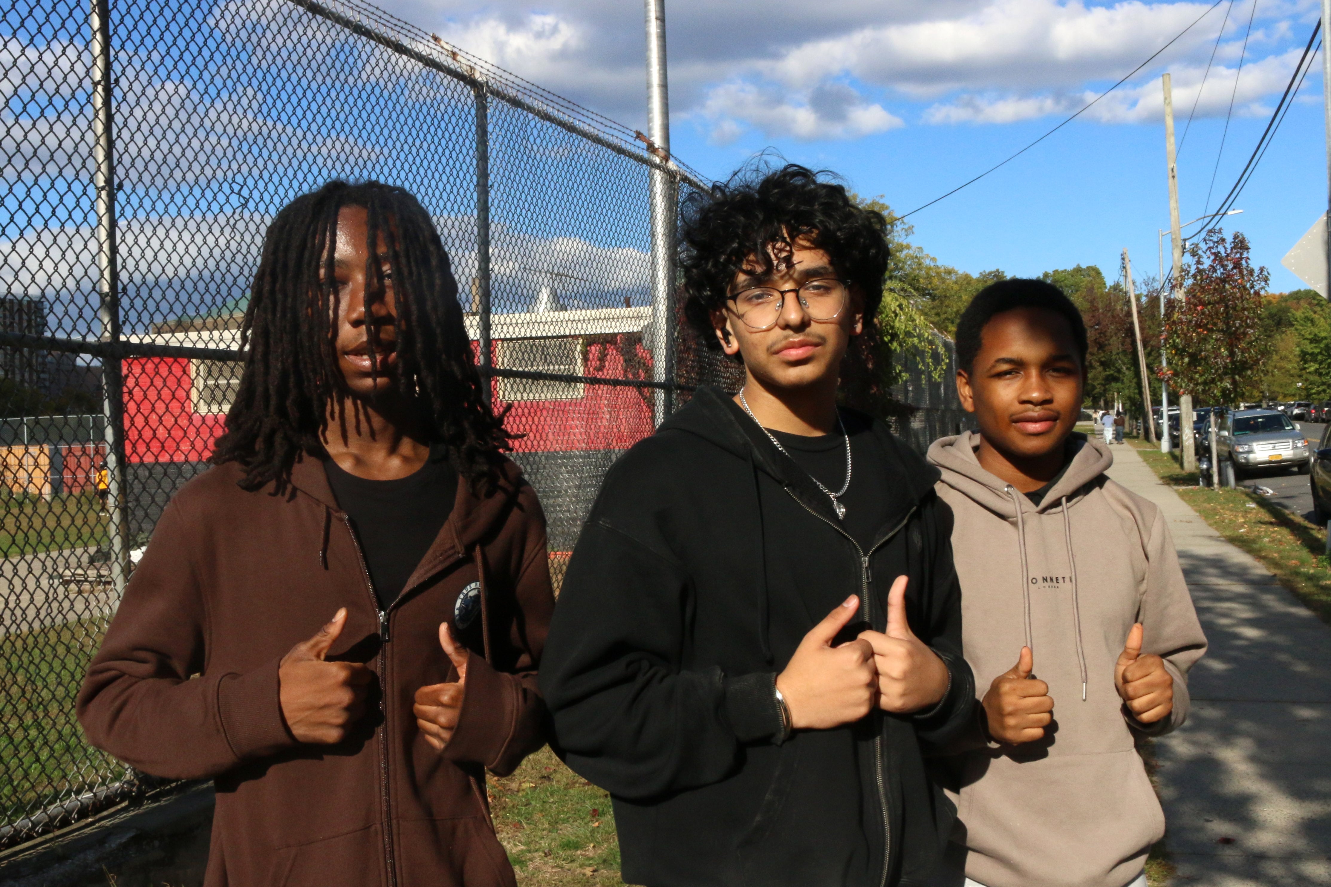 Three teens in sweatshirts stand at school.
