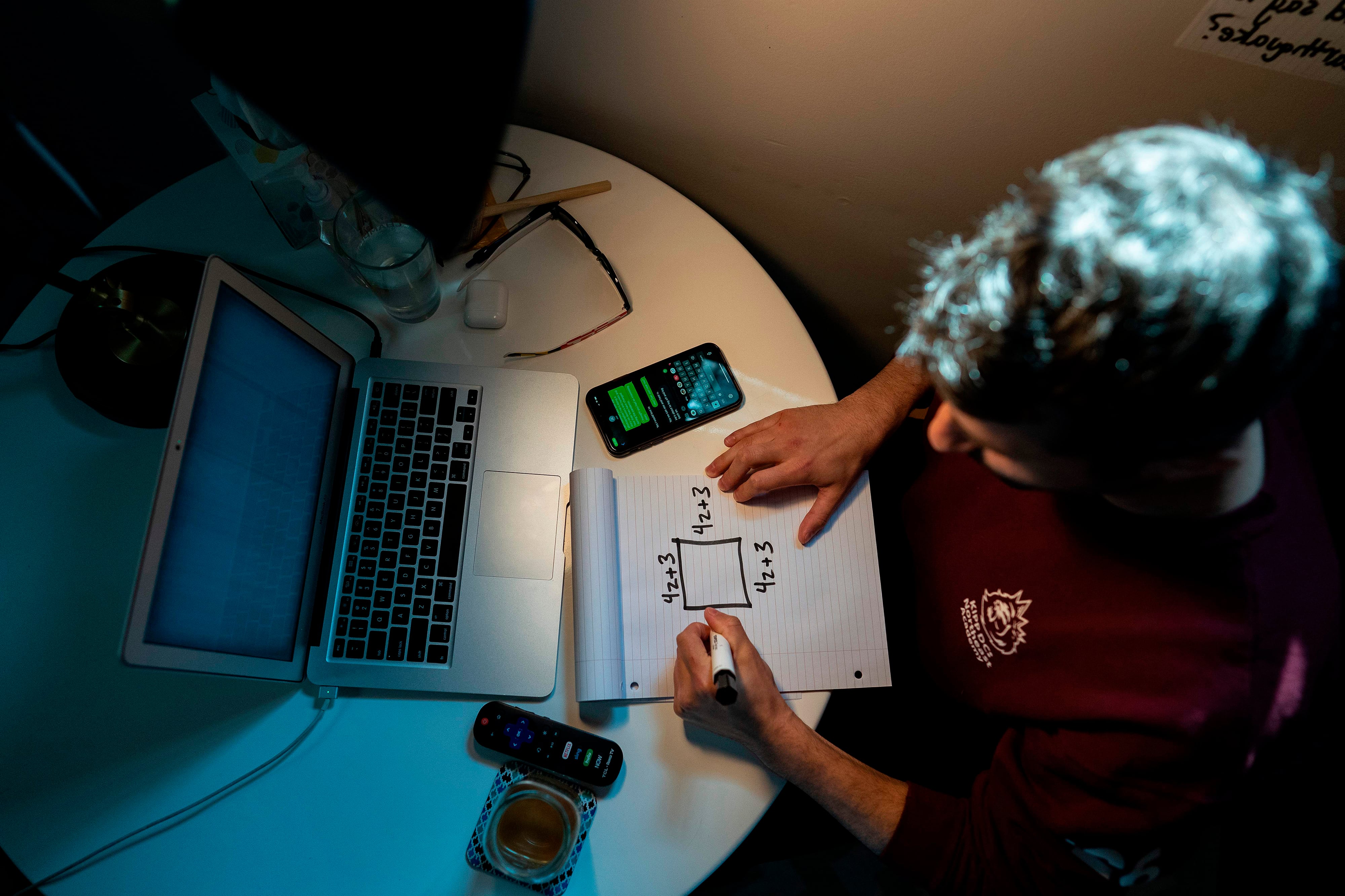 An aerial view of a student working on a laptop and sitting at a desk.
