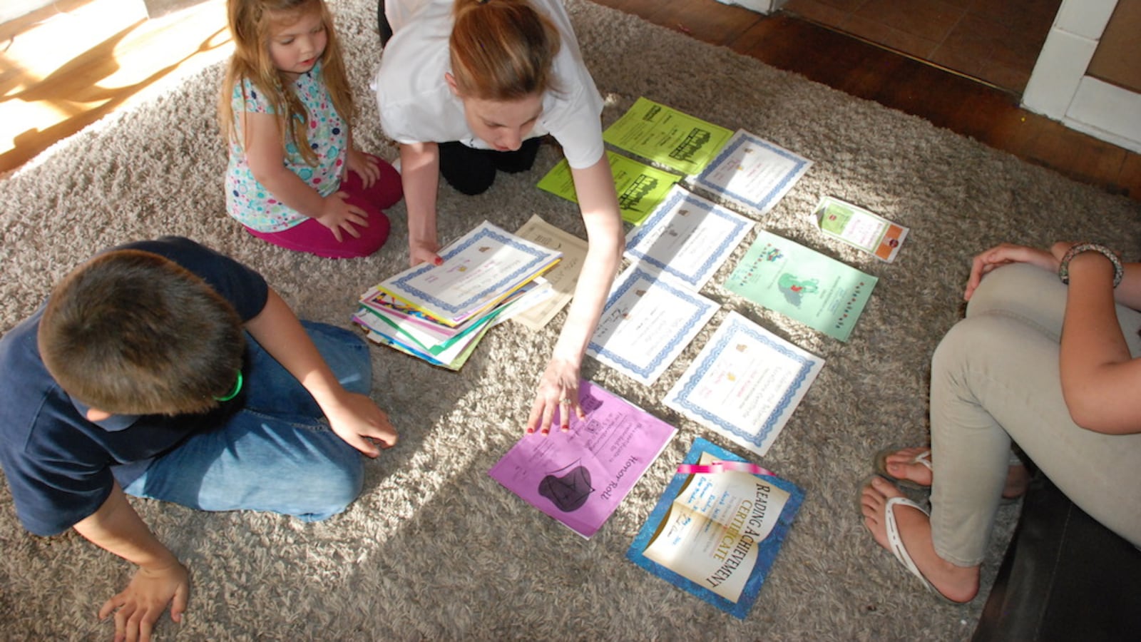 Julianne Williamson spreads out her children's academic awards from the Bessemer Academy in her living room in Pueblo. With her are her children Trinity, who will enter kindergarten this upcoming school year, Jacob, a third grader, and Ryane.