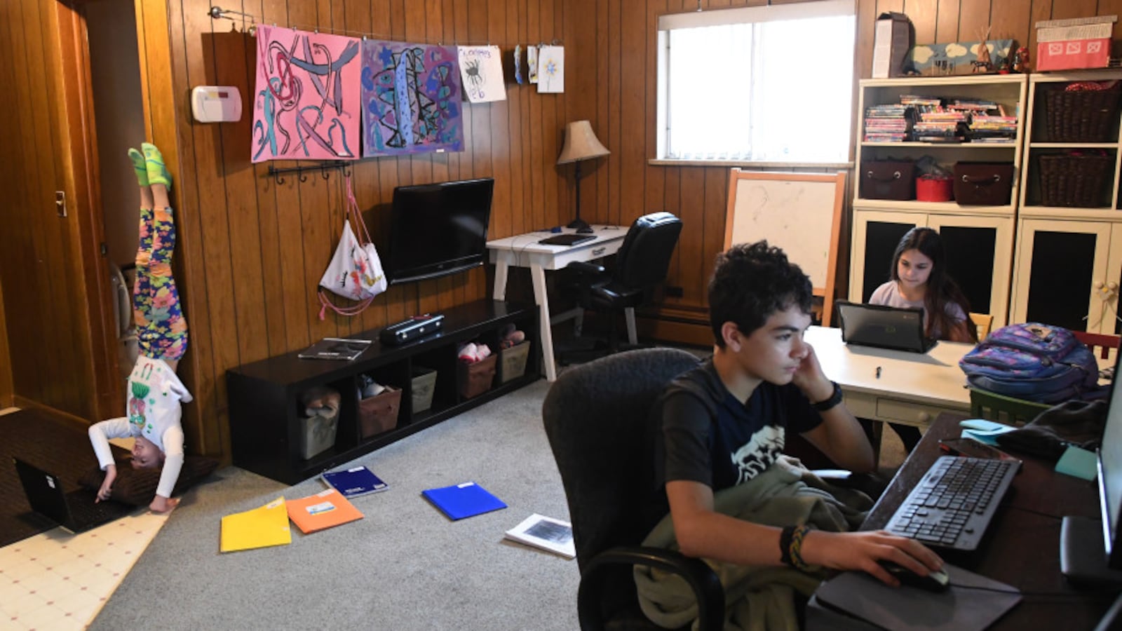 Eight-year-old gymnast Allie Vanderploeg, left, a second grader in Jeffco Public Schools, works with her brother, Kaden, 13, center, and her sister, Maddie, 11, at their home during the first day of online learning on March 17, 2020 in Lakewood.