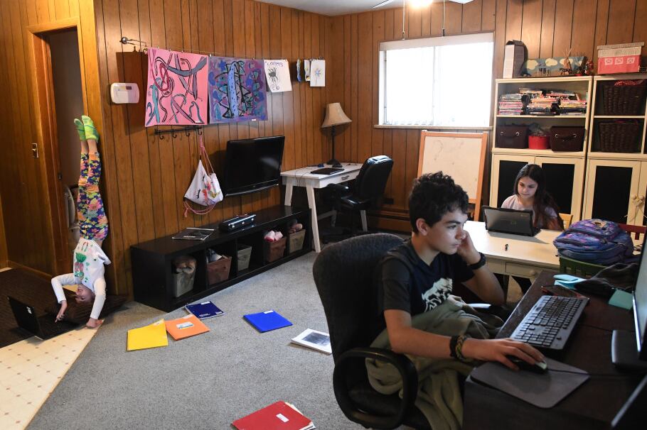 Eight-year-old gymnast Allie Vanderploeg, left, a second grader in Jeffco Public Schools, works with her brother, Kaden, 13, center, and her sister, Maddie, 11, at their home during the first day of online learning on March 17, 2020 in Lakewood.