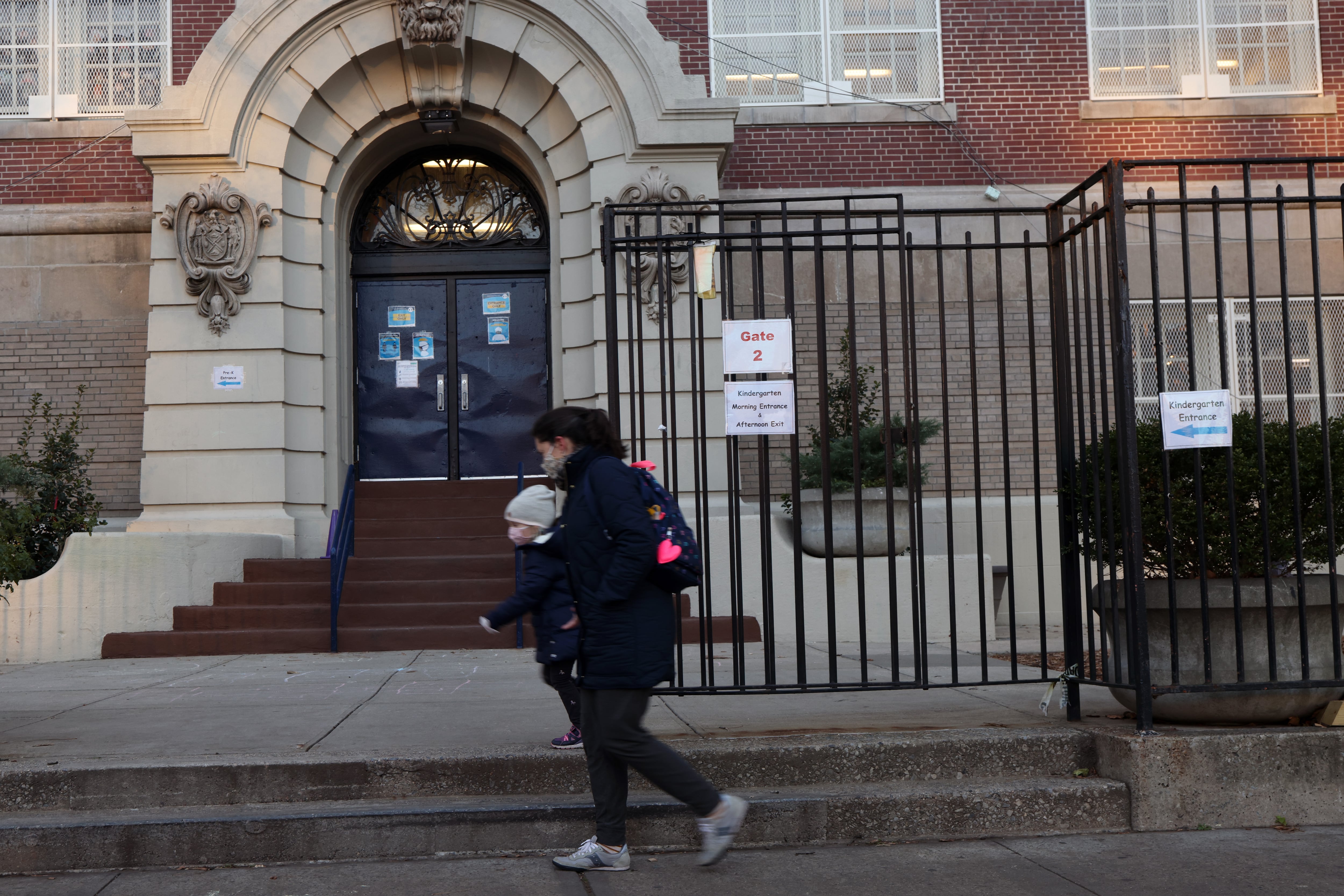 People walk by a public school in Brooklyn on Nov. 18, 2020. Public schools in New York City, the largest school district in the nation, will close again on Thursday, officials have said after the city reached a 3% Covid test positivity rate.