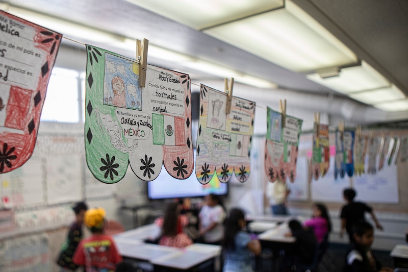 Student work hangs on clothes pins in a classroom.