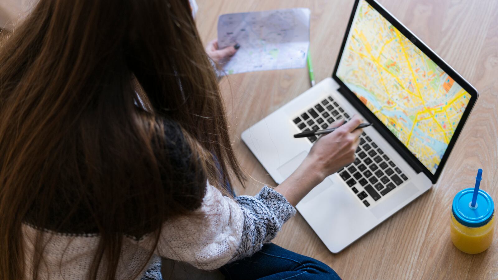 Young woman sitting on the floor looking at map on laptop