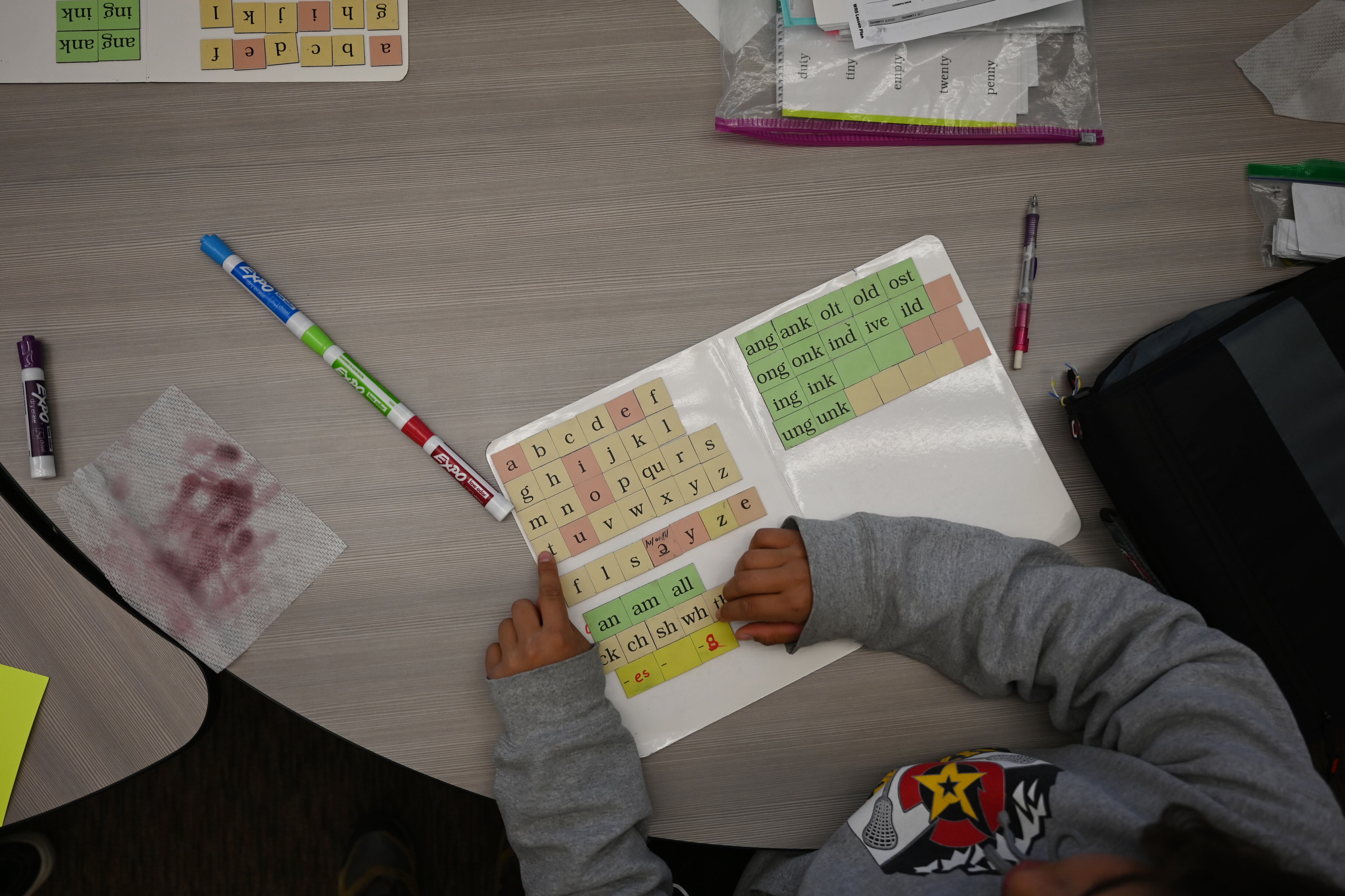 A student works on letter sounds, using a board with magnetic letters at a circular table.