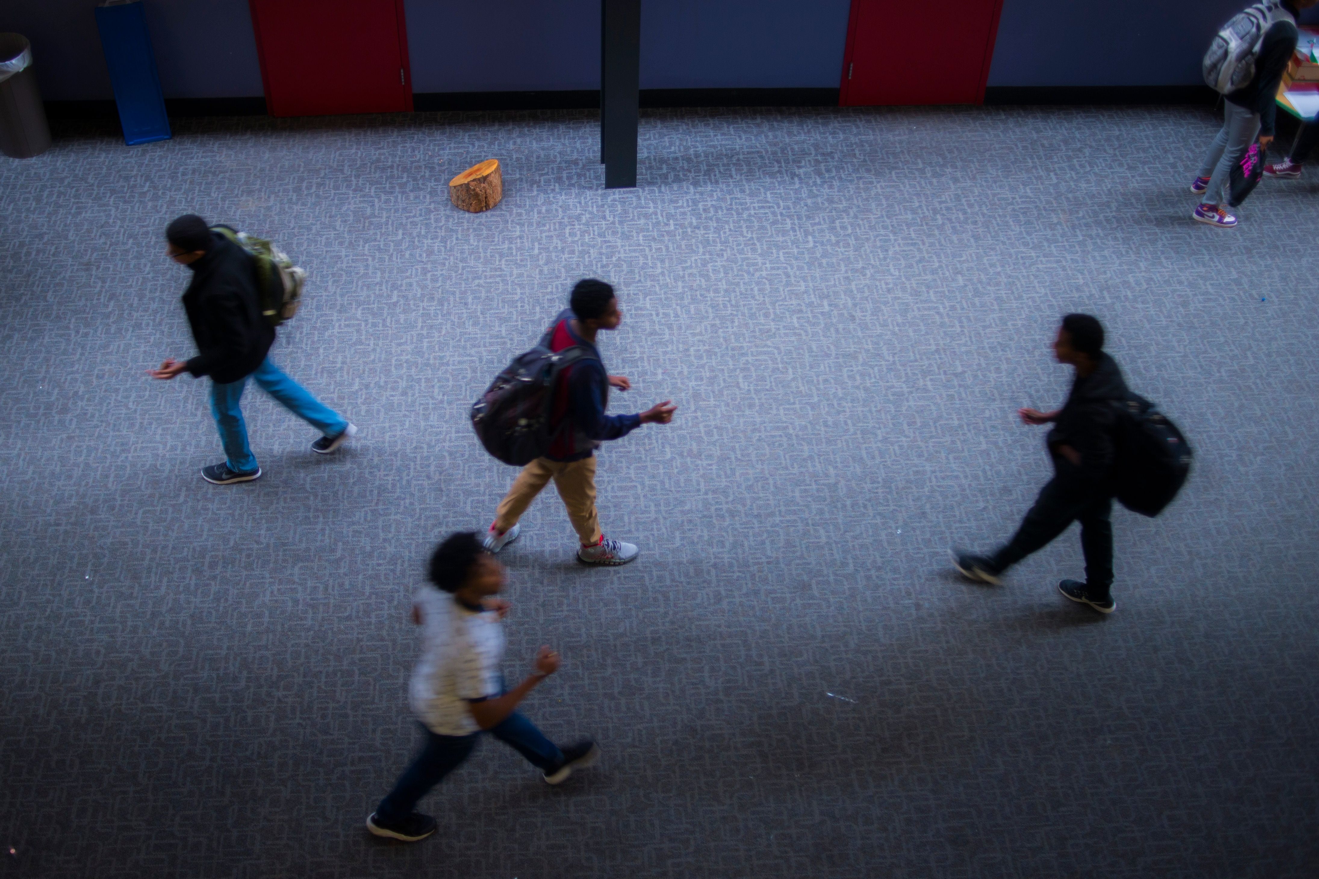 Students walk apart in a high school hallway.