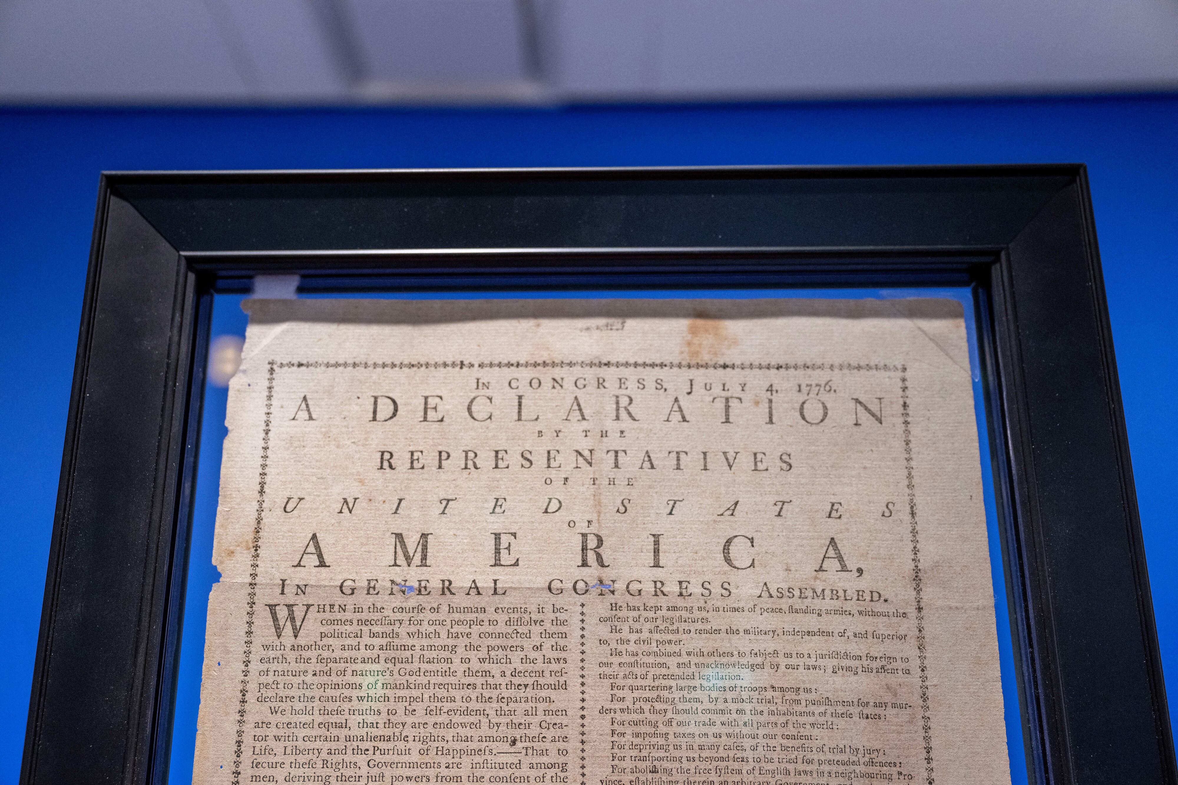 A framed Declaration of Independence in front of a blue wall.