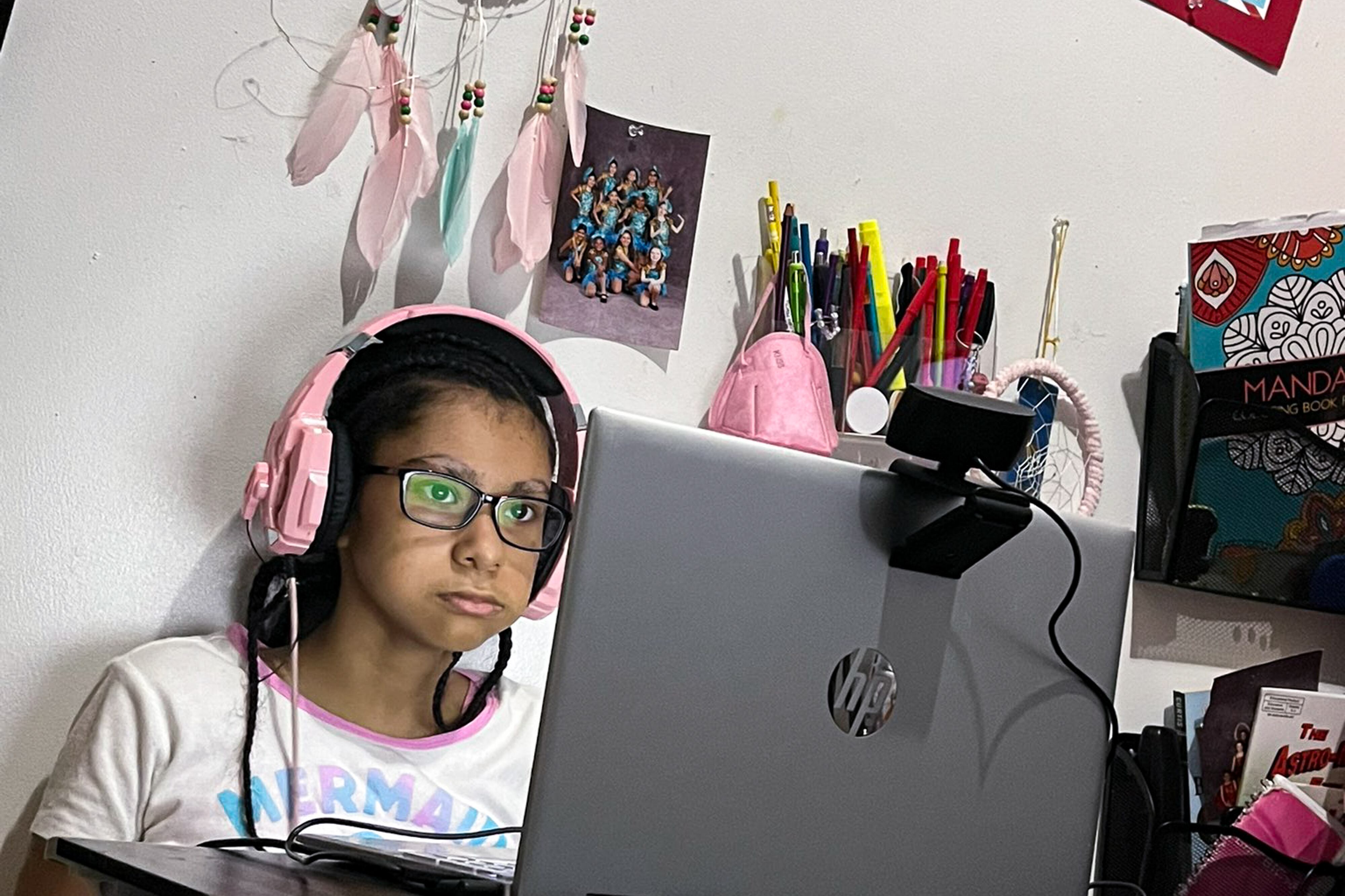 A girl with headphones looks at a laptop.
