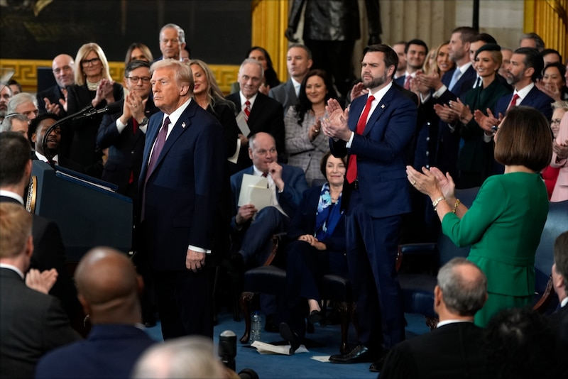 President Donald Trump stands in the U.S. Capitol Rotunda after being sworn in. Elected officials around him clap.