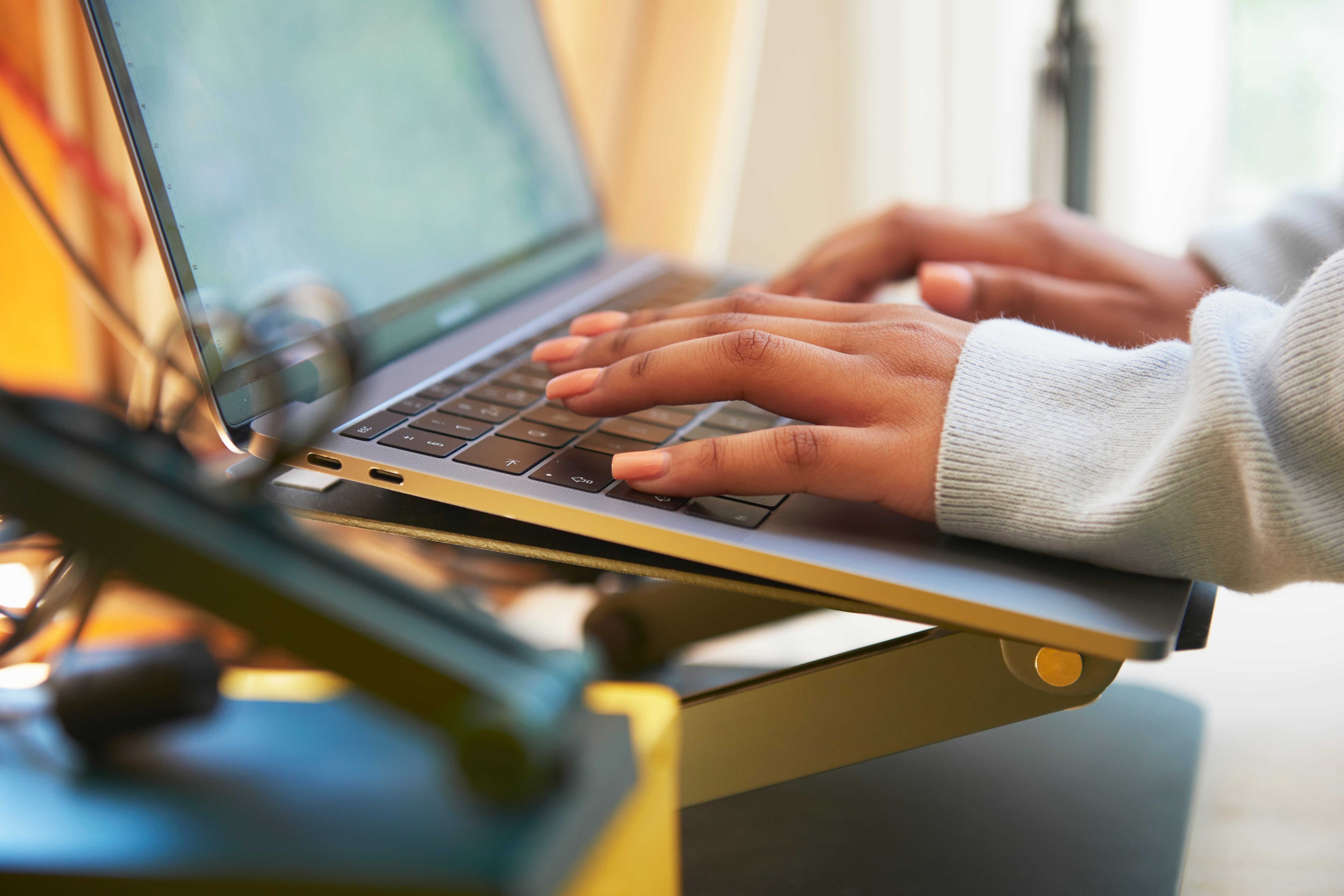 Close up of a pair of hands typing on a laptop keyboard.