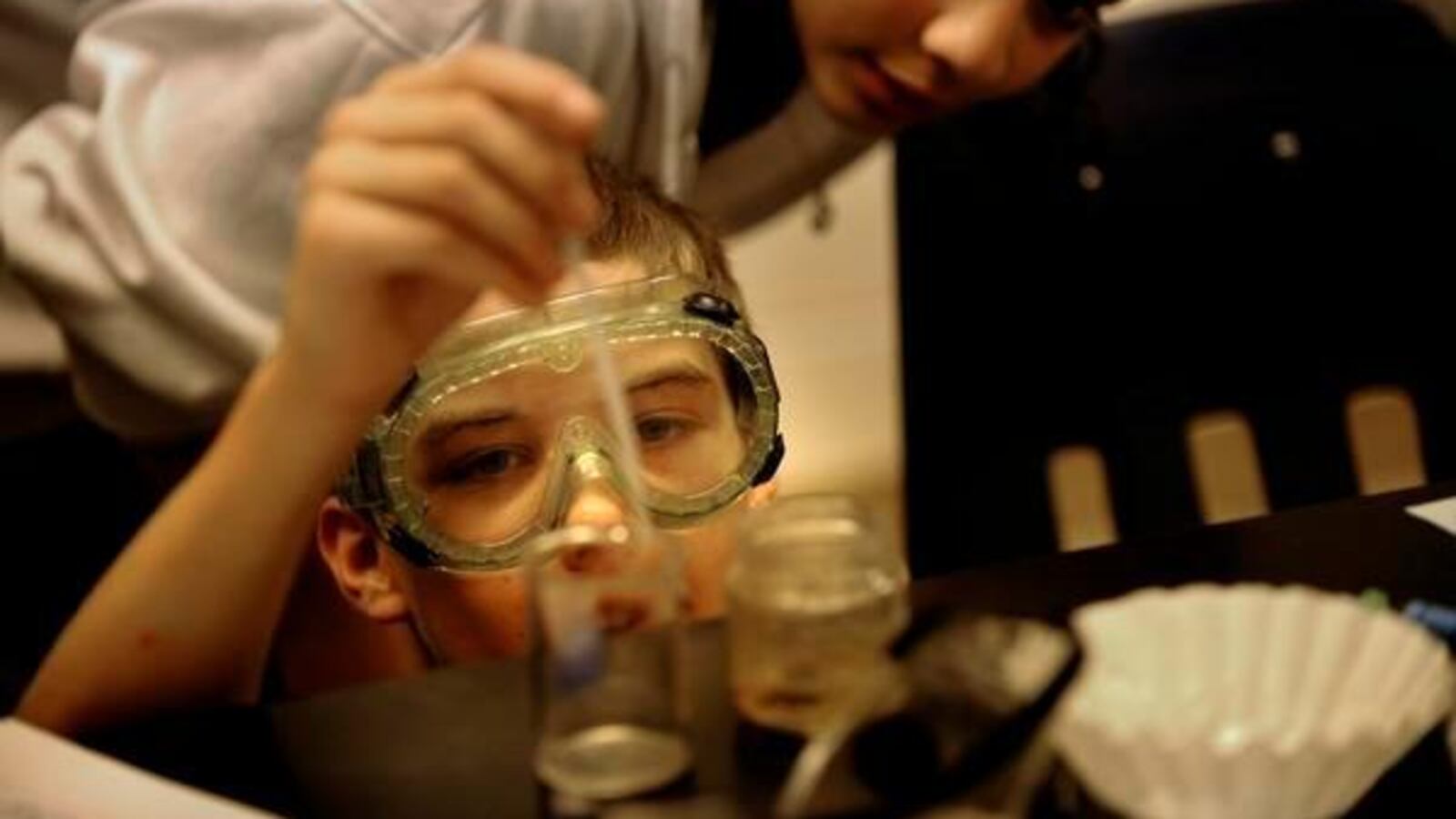 Justine May watches Prairie Middle School classmate Nate Stevens remove oil from the top of a water sample as his science class works on solving the problem of getting sludge out of their water samples. (Photo by Joe Amon, The Denver Post)