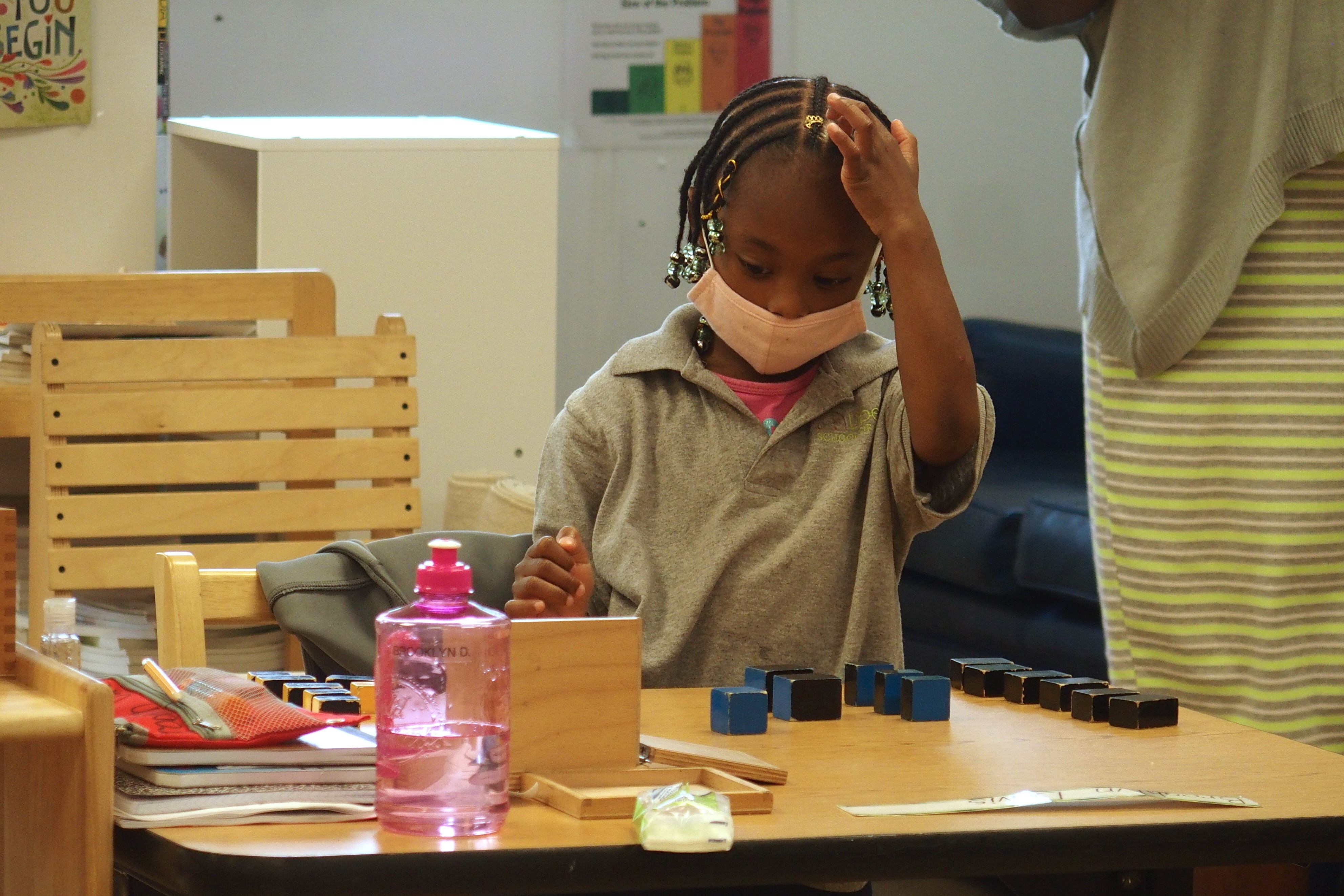An elementary school student in class while wearing a mask. 
