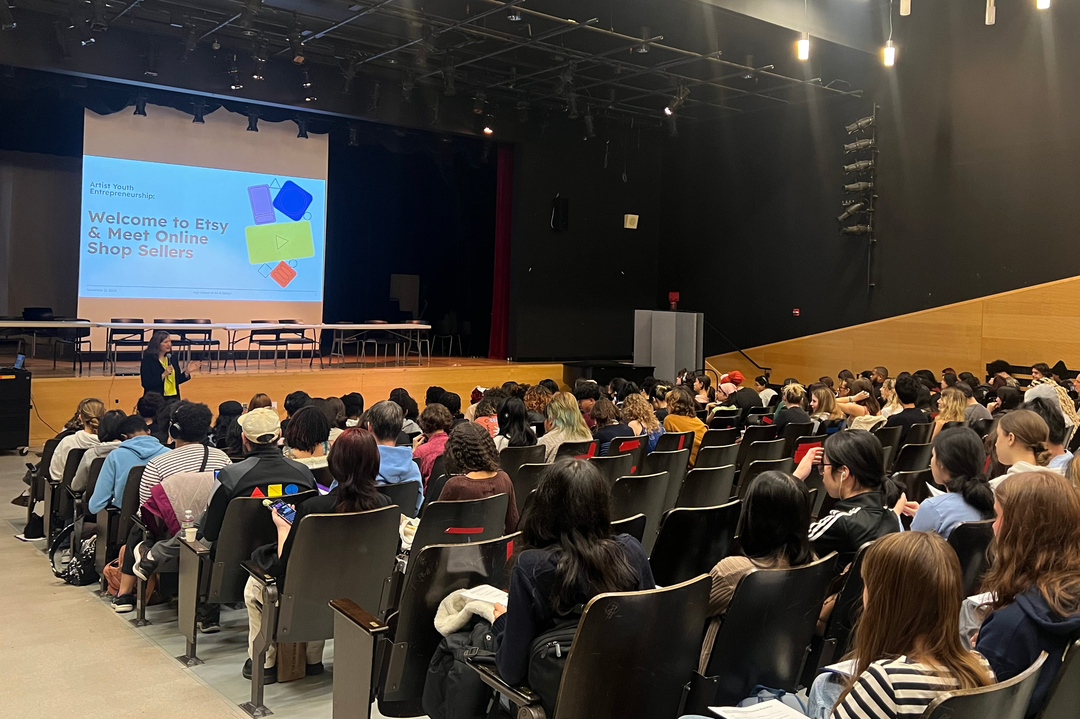 A large group of high school students sit in an auditorium.