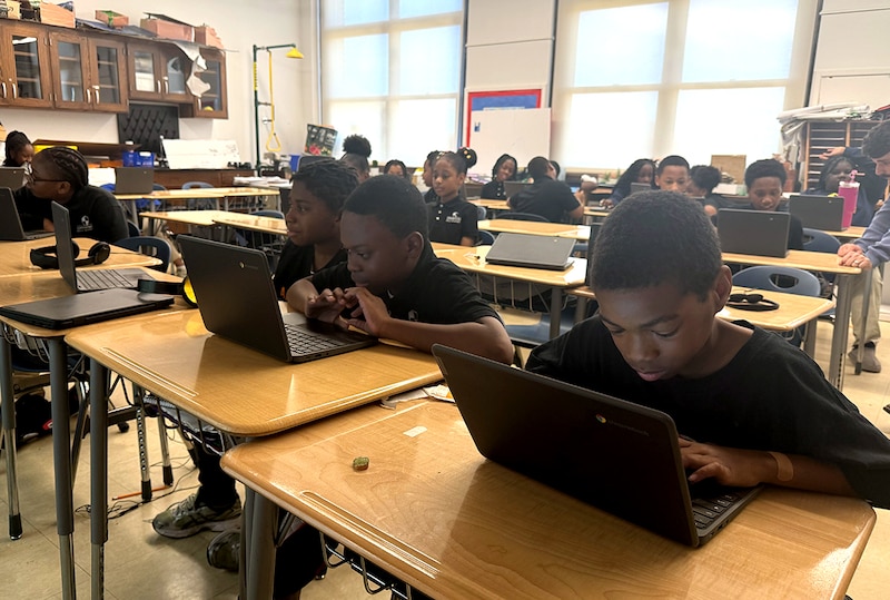 Students in dark shirts work on laptops.