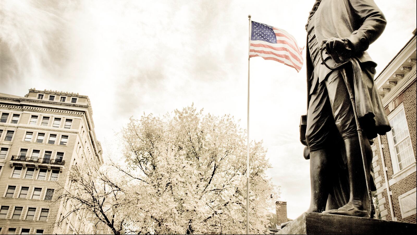 A statue of George Washington with the American flag in the background in front of Independence Hall.