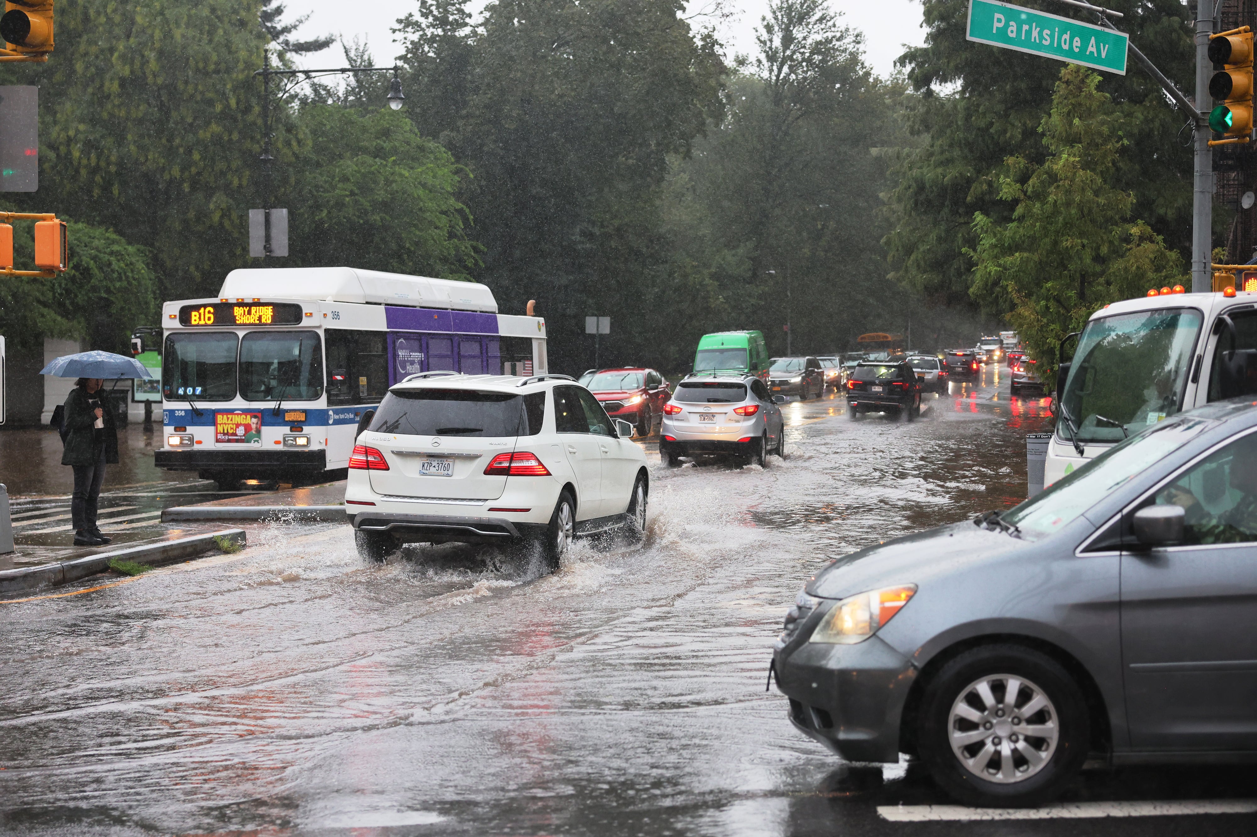 Cars drive through a flooded street.