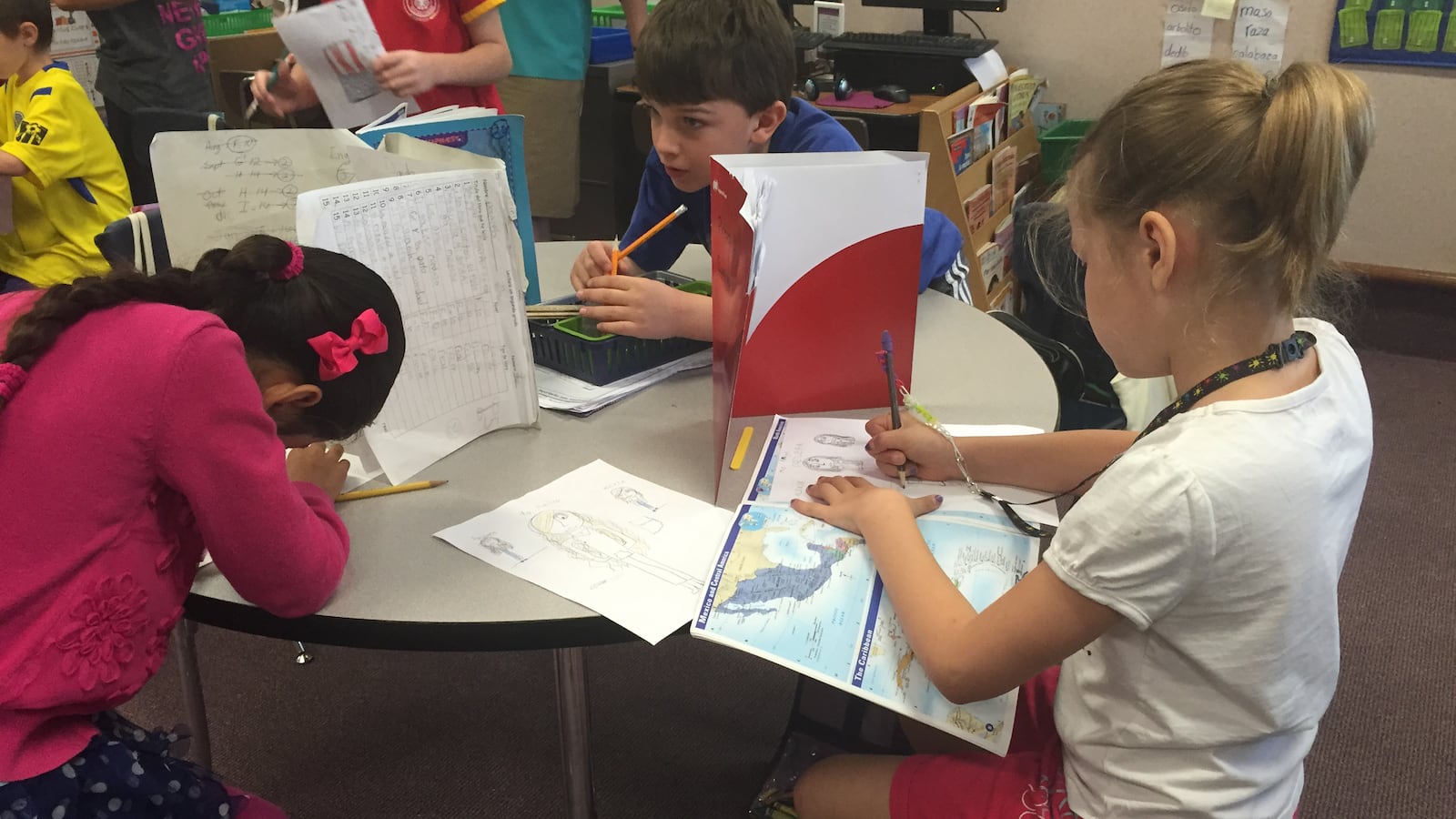 Three girls in Mabel Ramos’ third grade class at Forest Glen Elementary School work on writing letters to students in Cuba. Immersion classes are primarily taught in Spanish.