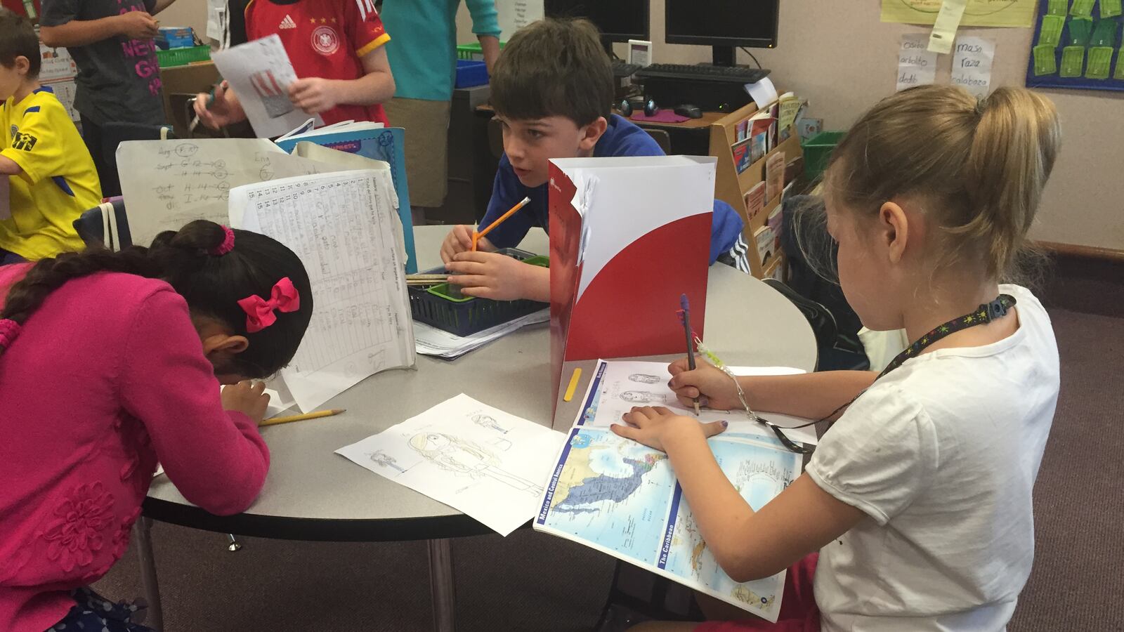 Three girls in Mabel Ramos’ third grade class at Forest Glen Elementary School work on writing letters to students in Cuba. Immersion classes are primarily taught in Spanish.