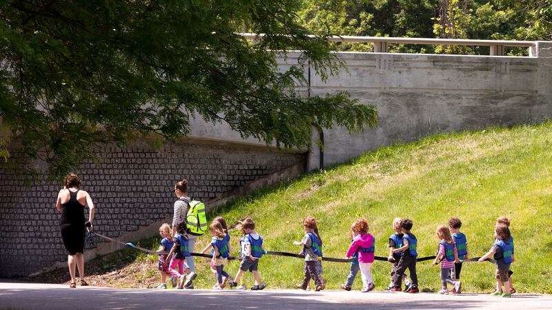 Daycare children on a long leash and their caretakers enjoy a walk through a Chicago park