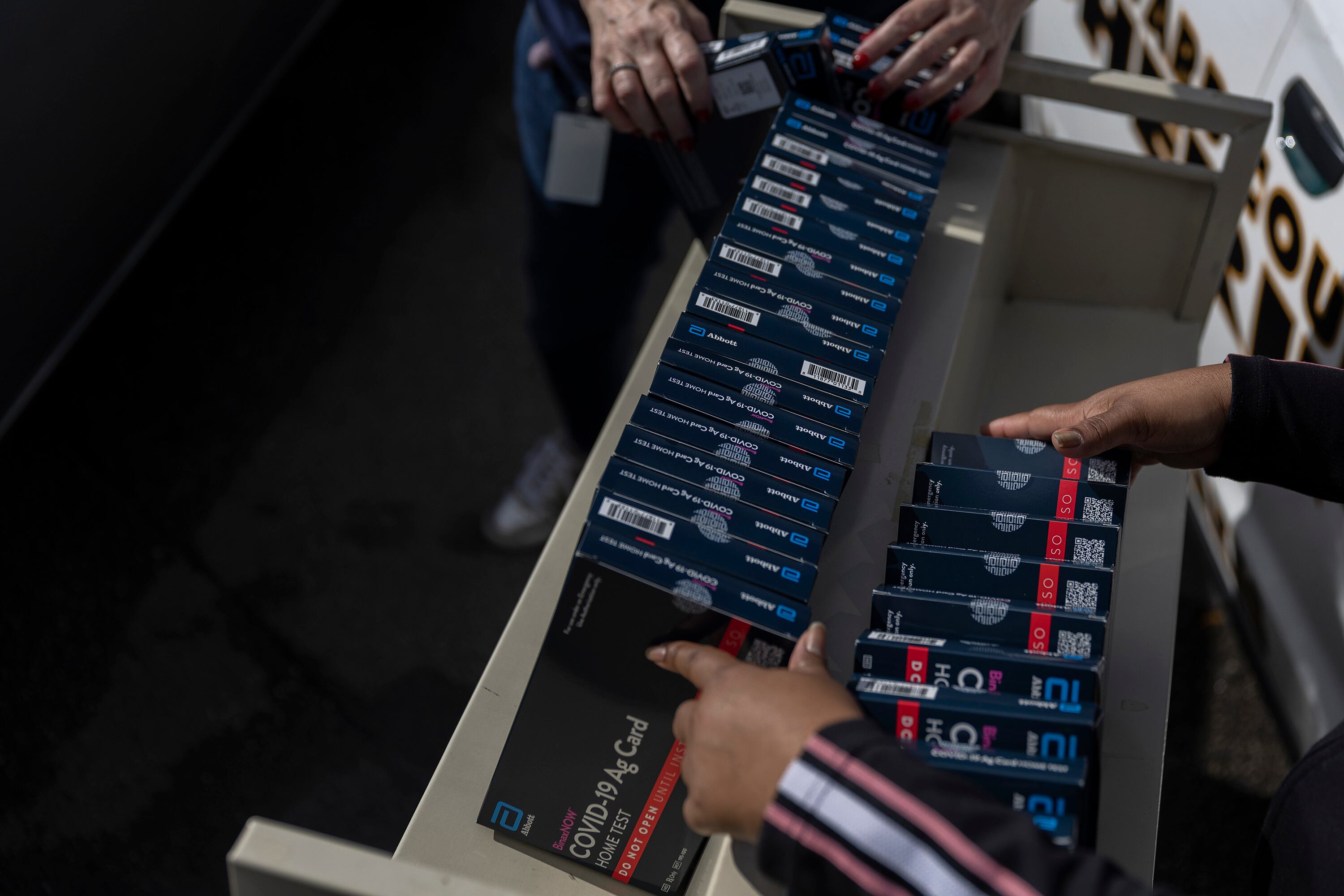A close-up shot of hands and at-home COVID tests.