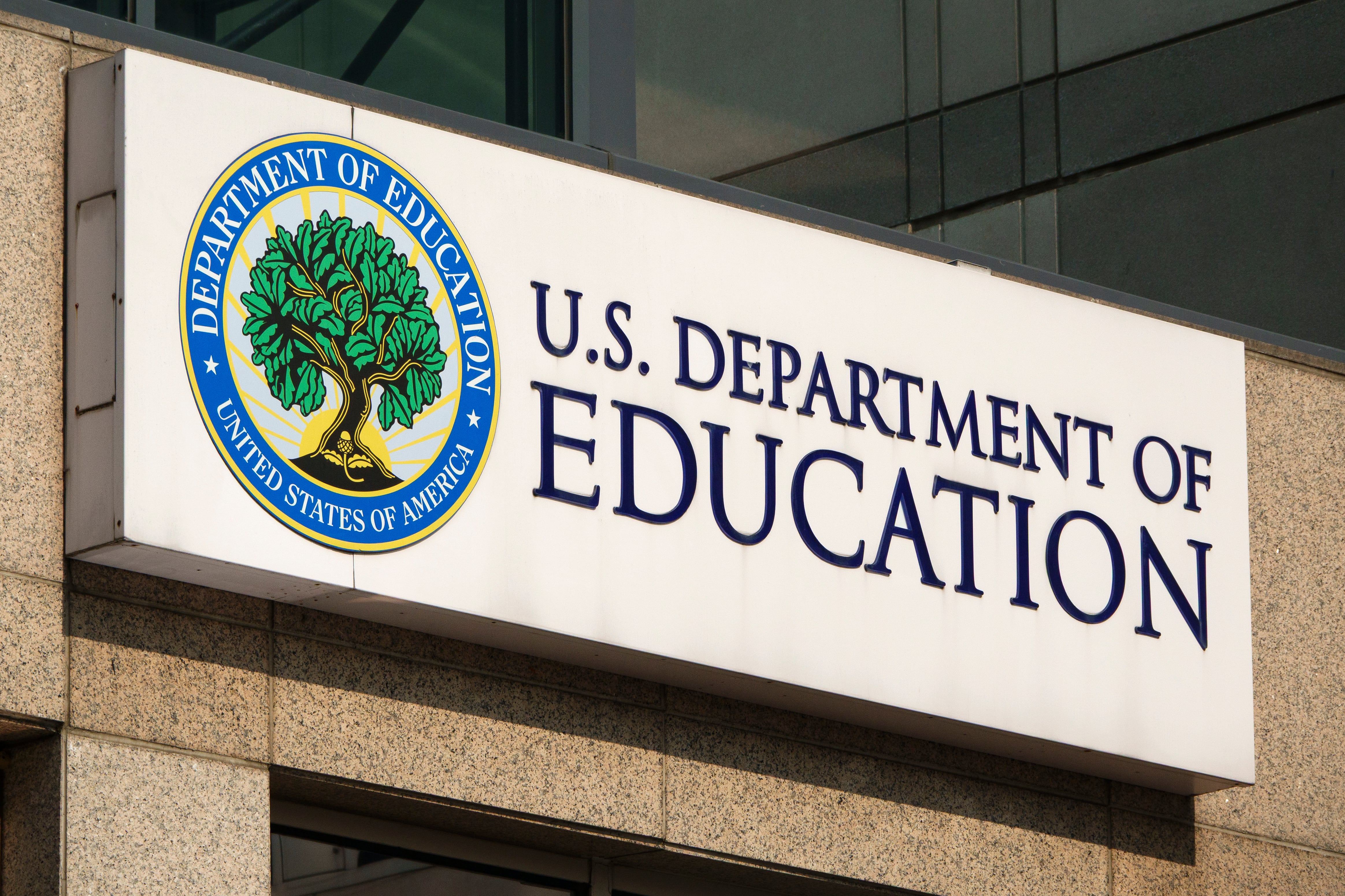 A white sign with blue letters hangs outside a building.