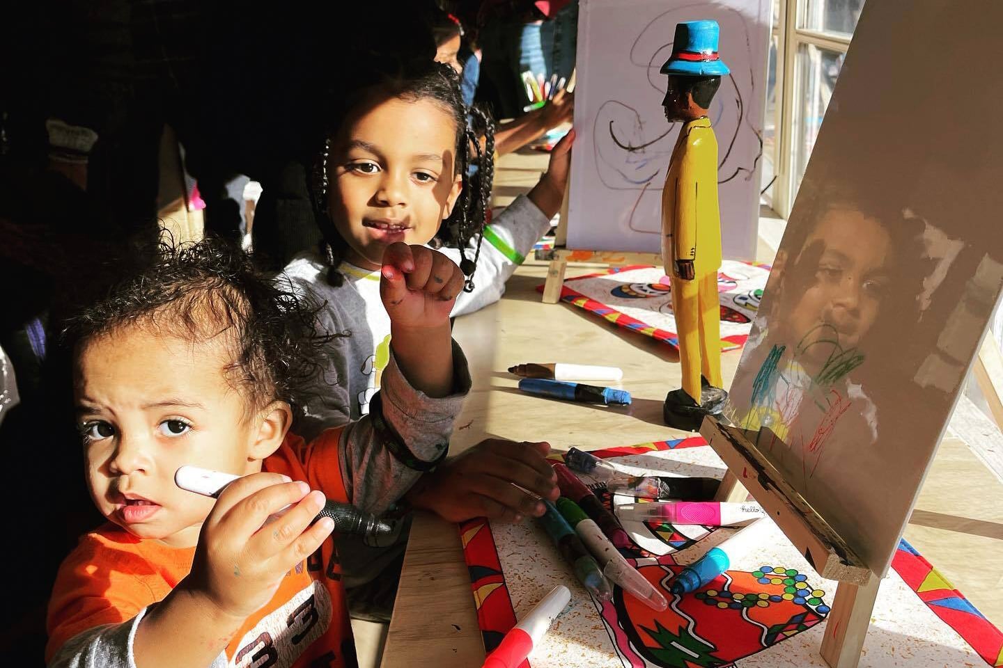 Two young children in beautiful window light and art projects.