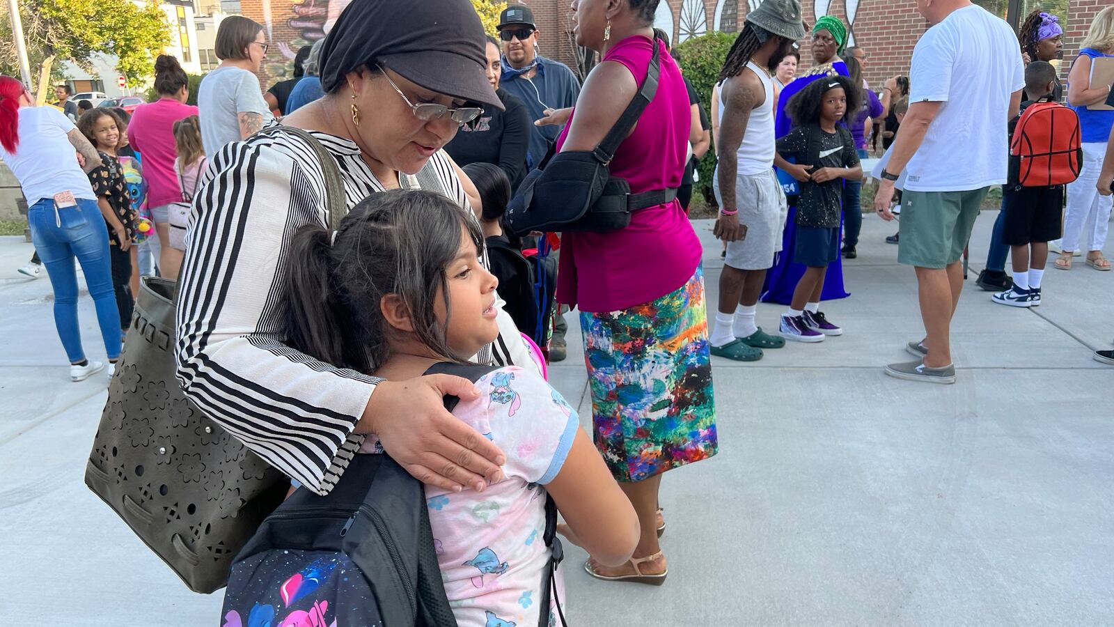 A mom hugs a 7-year-old daughter outside school.