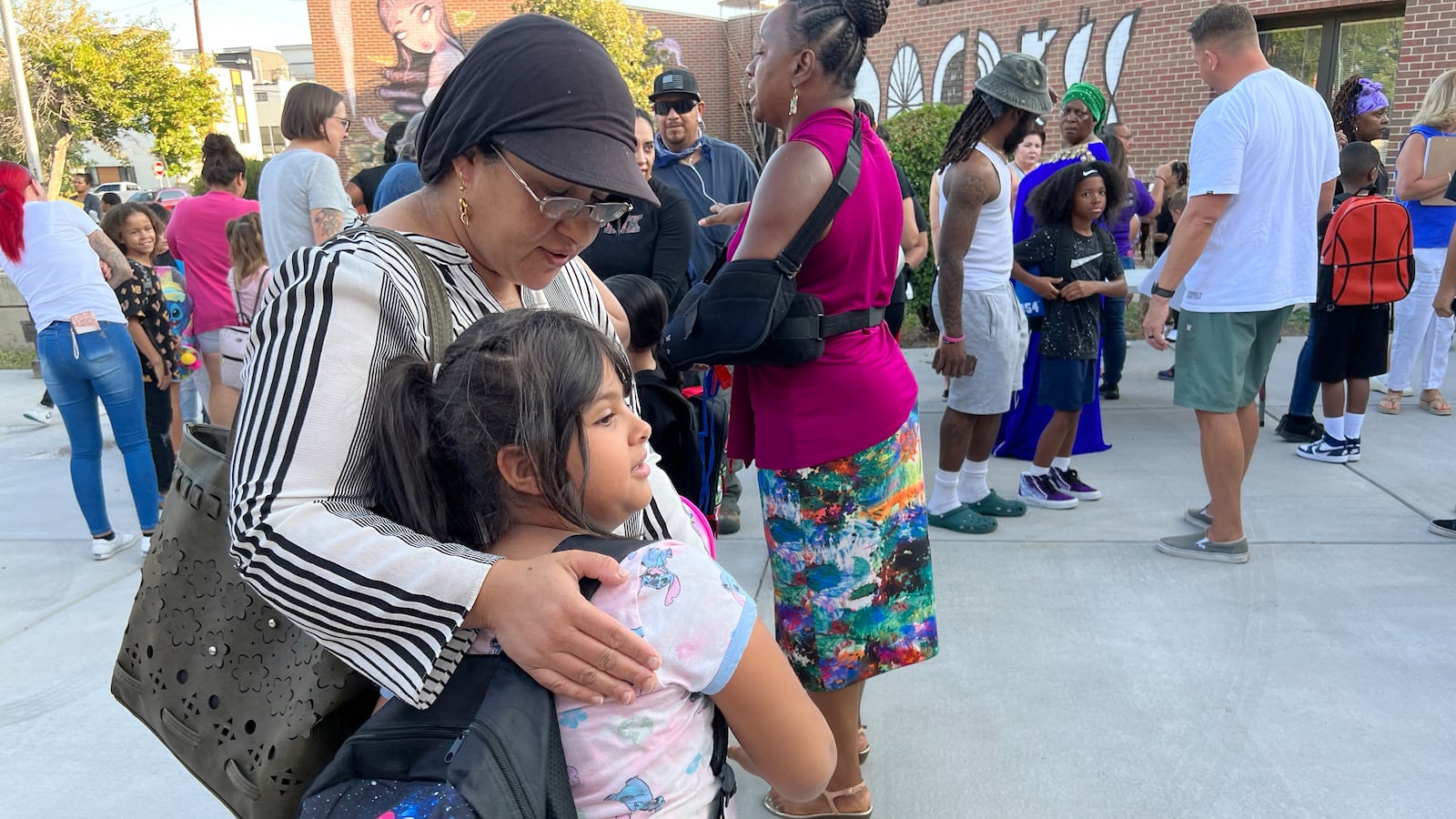 A mom hugs a 7-year-old daughter outside school.