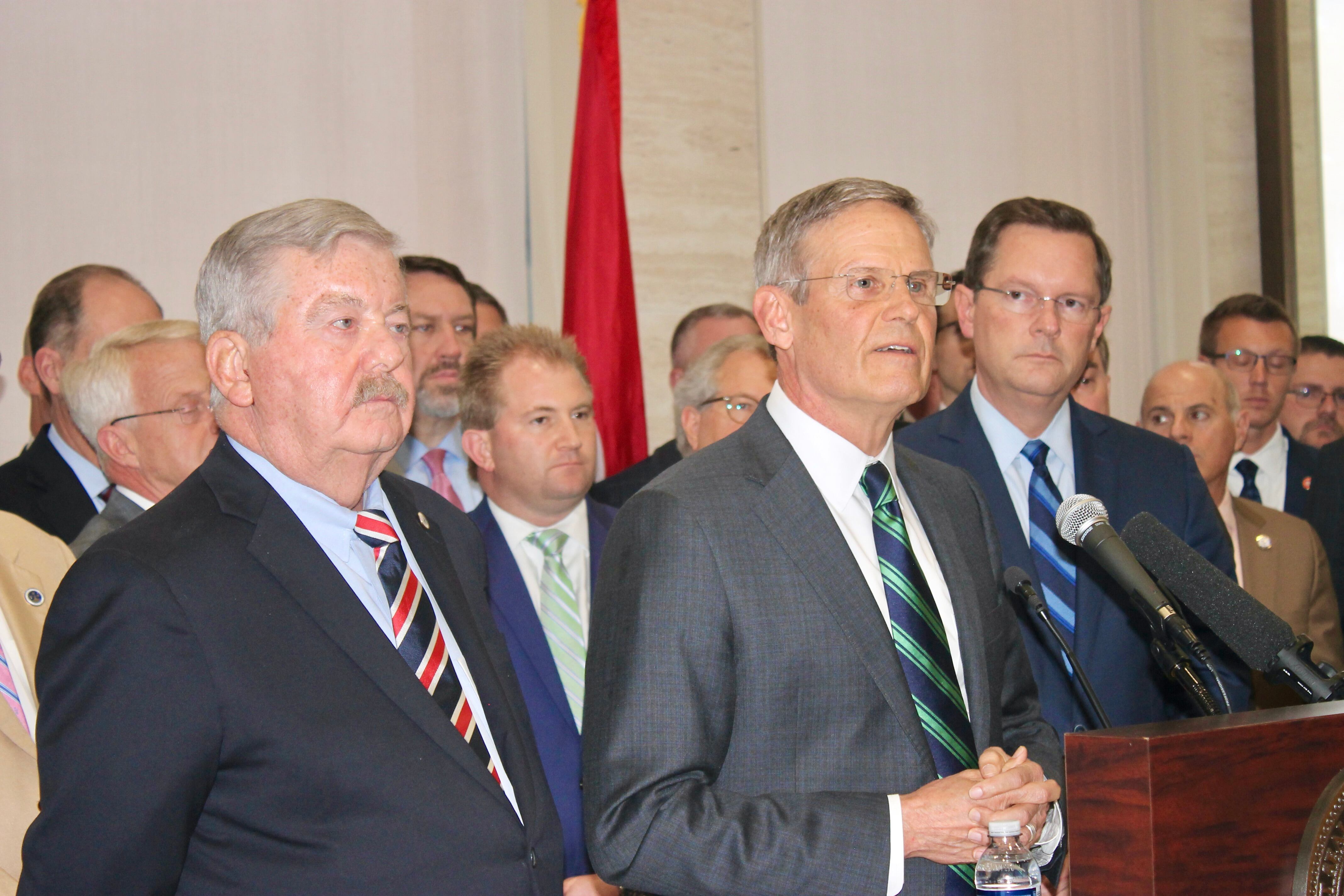A group of men wearing business suits stand in front of a podium.
