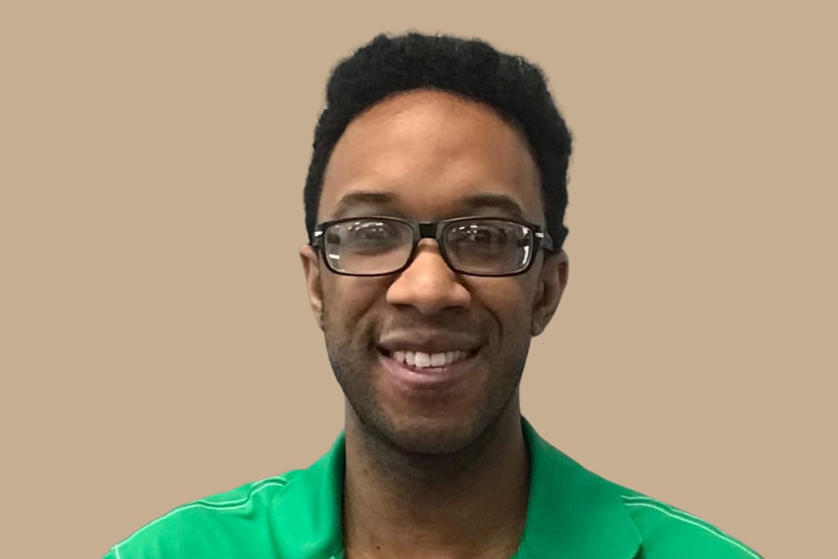 Chicago music teacher Reggie Spears, wearing a green shirt with a collar, smiles at the camera.