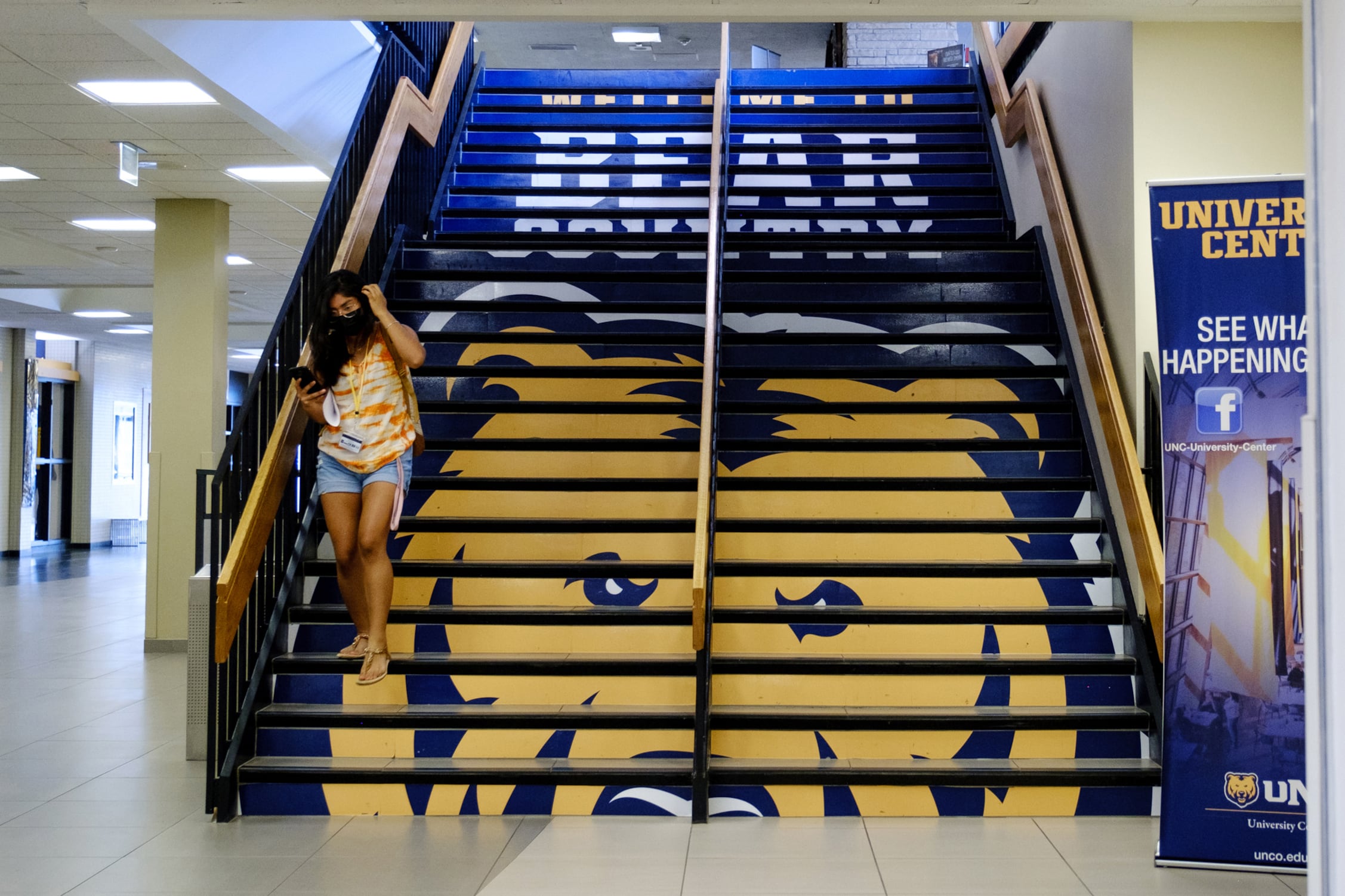 A woman walks down yellow-and-blue steps.