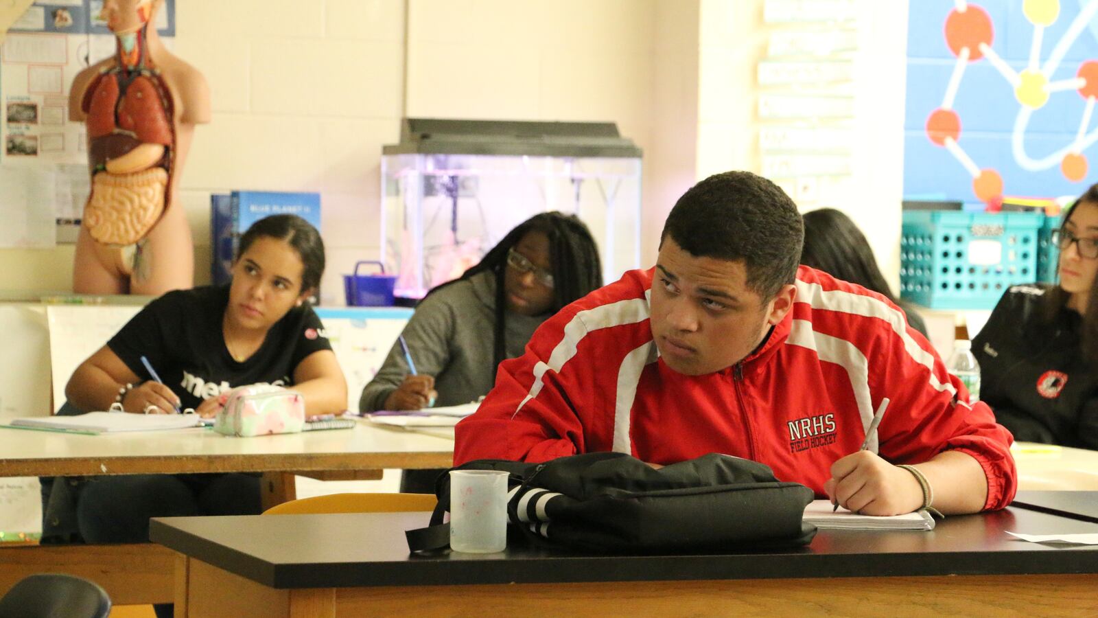 Hannah Olaniyi (center) and Gabriel De Oliveira take a college-level biology class at East Side High School.