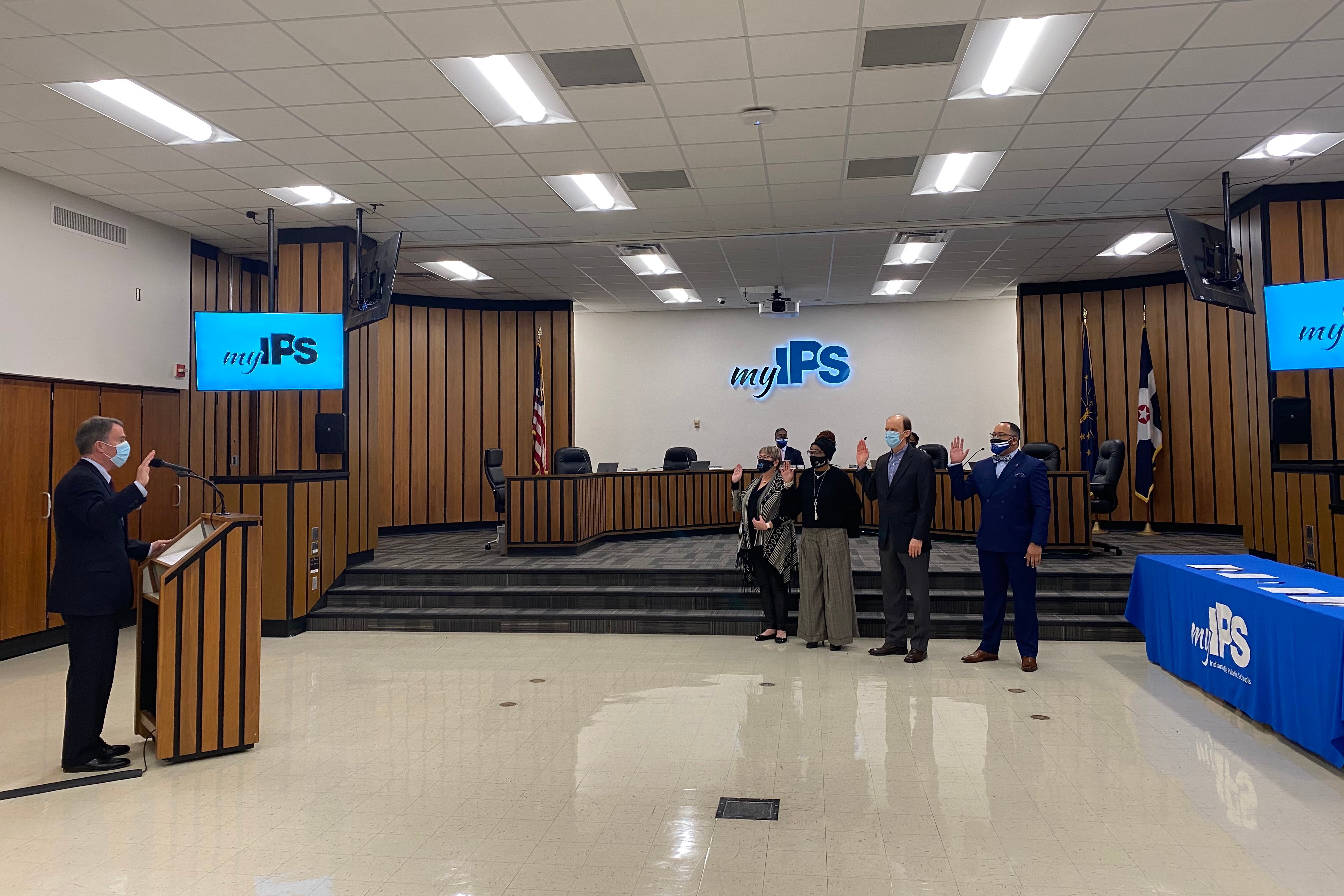 Indianapolis Mayor Joe Hogsett holds up his right hand as four board members hold their right hand up during a swearing in ceremony as new board members.