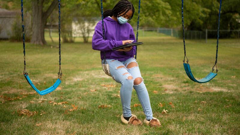 Middletown High School students Pilar Brooks sitting outside on a swing wearing a mask.