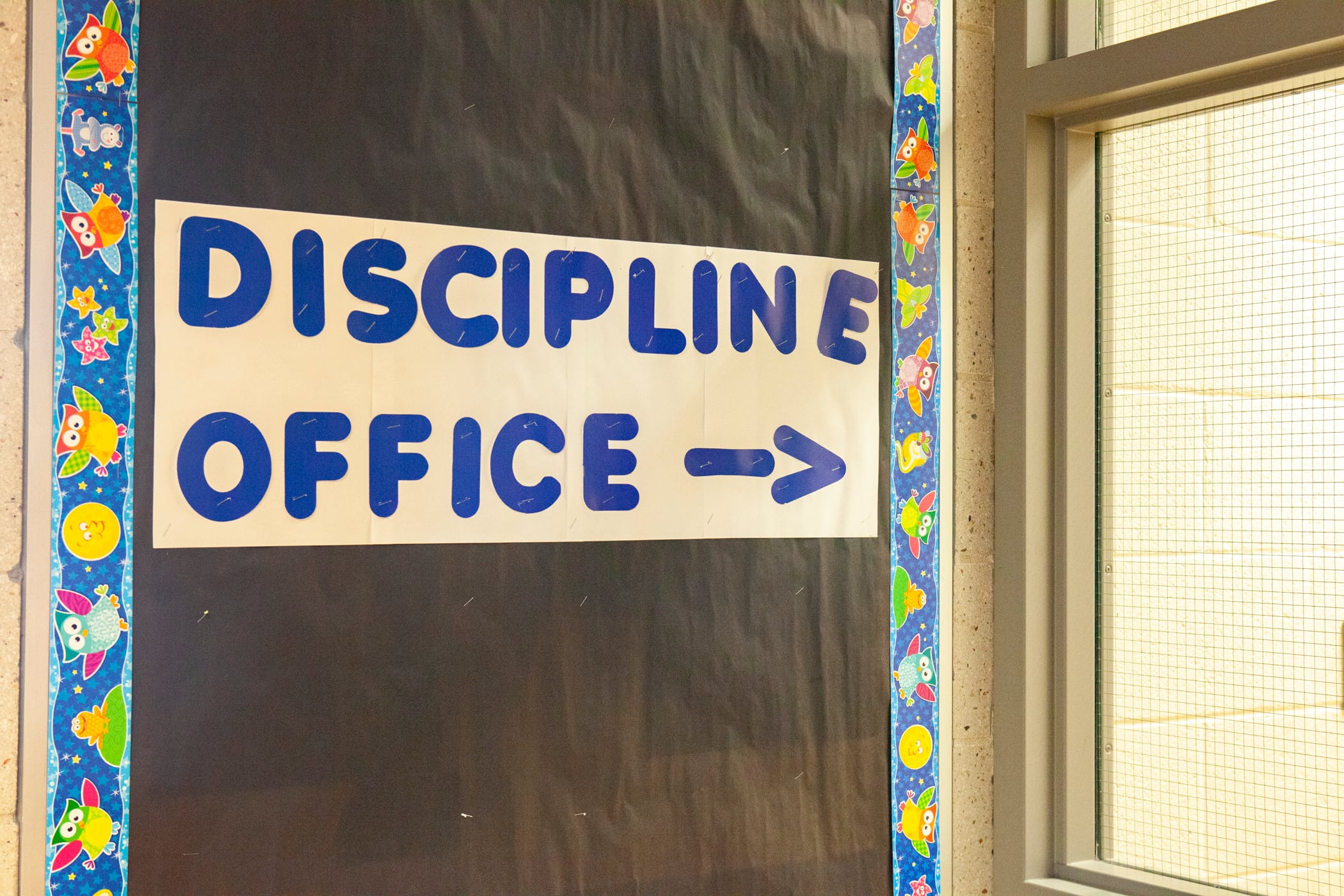 A colorful sign on the side of a door in a school building that reads "Discipline Office."