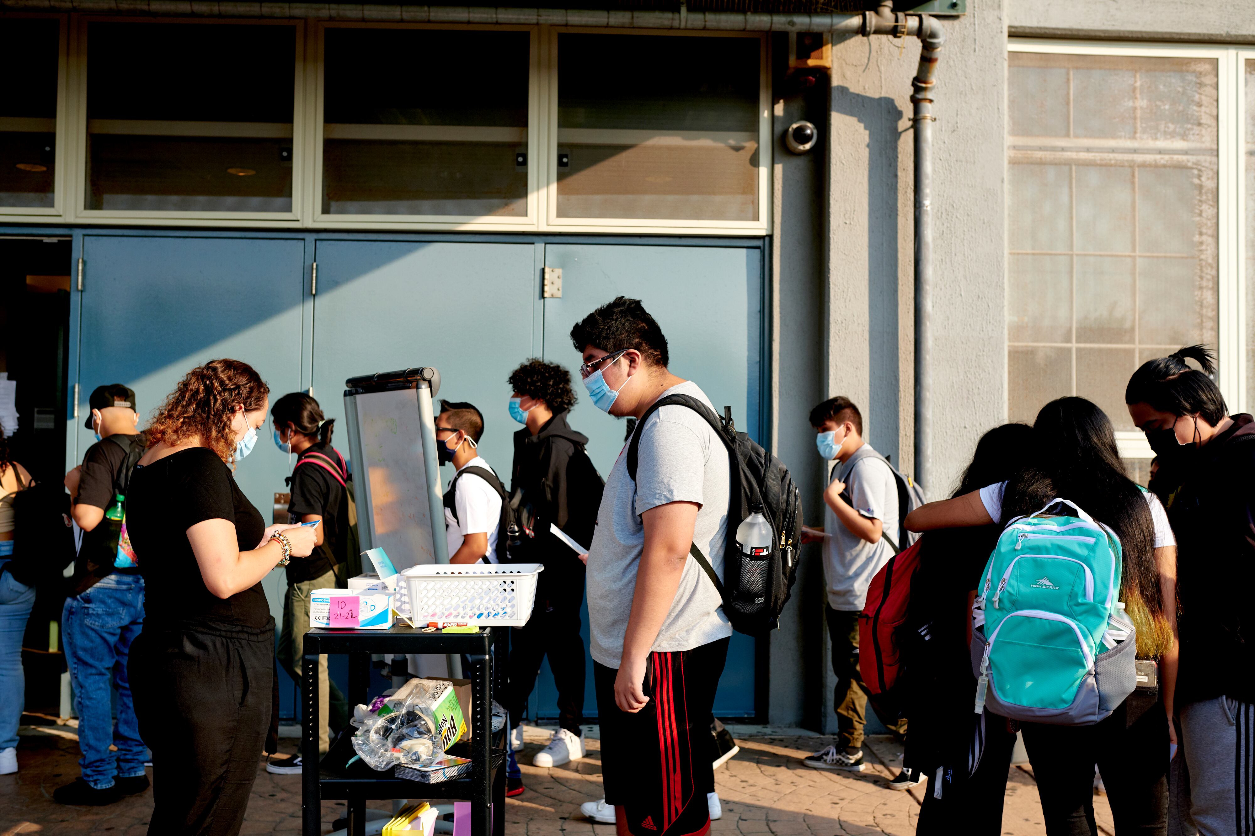 Students wait for COVID screening forms outside of the entrance of their school.