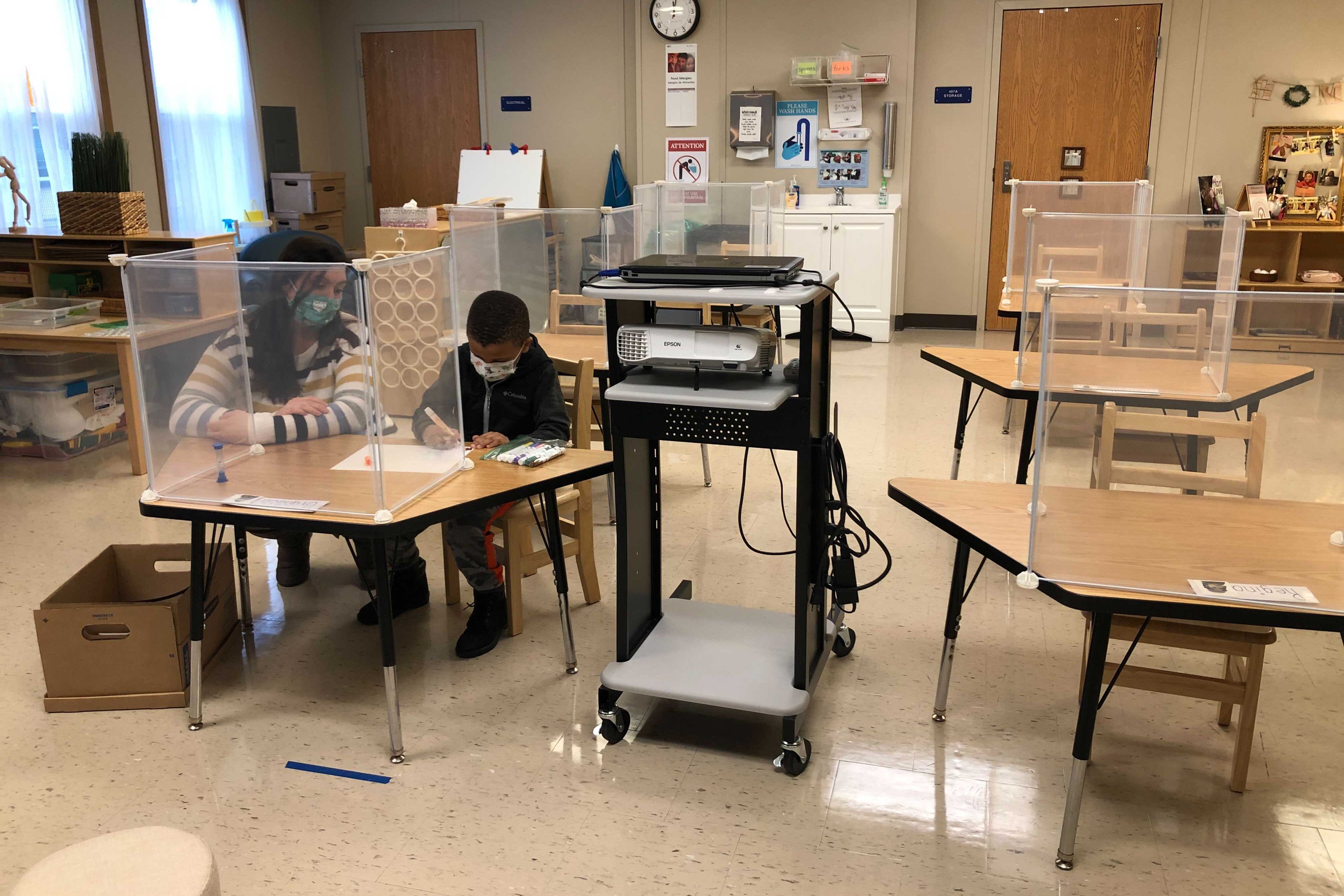 Teacher and student wearing masks in a mostly empty classroom.