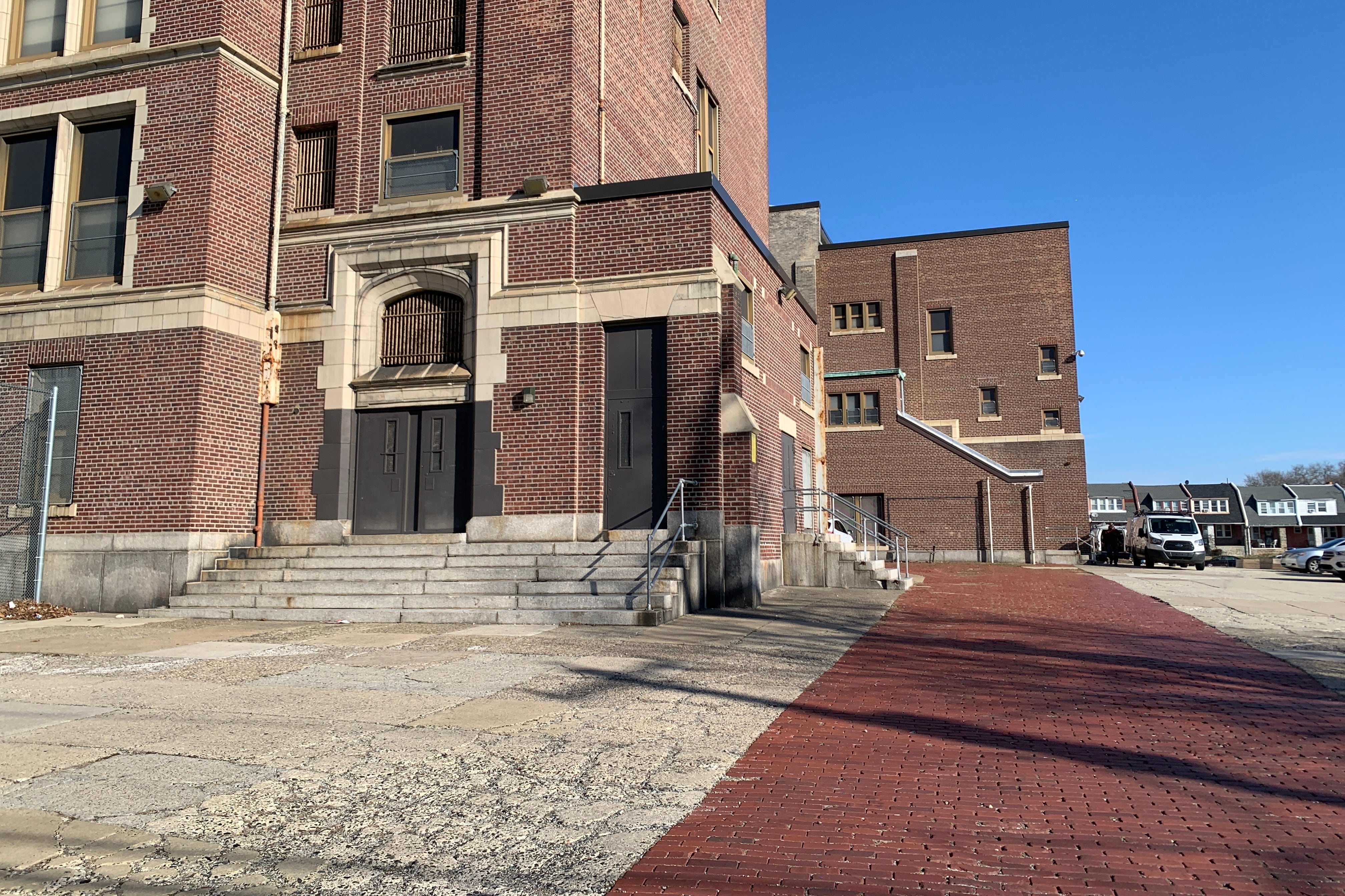 A red and brown brick building with a wide red brick path to the right.
