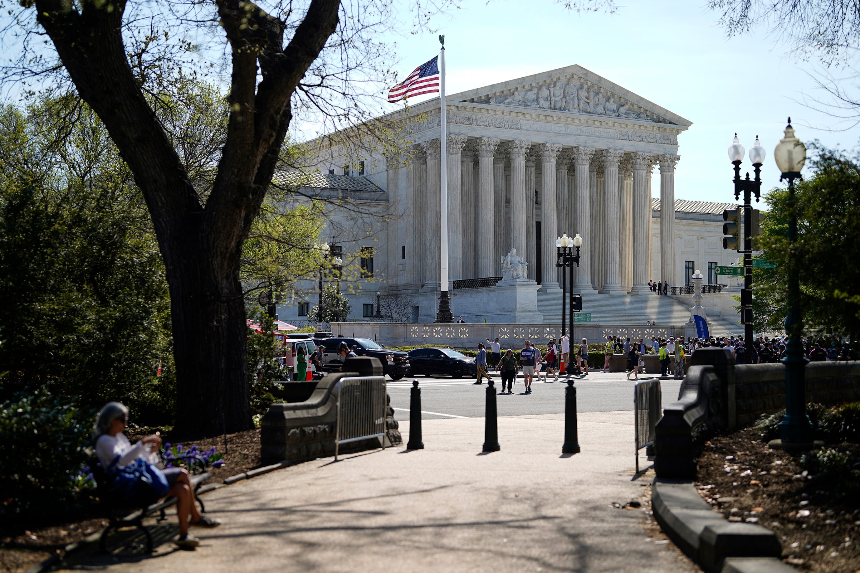 A tall stone building with columns and a US flag and trees in front of it.