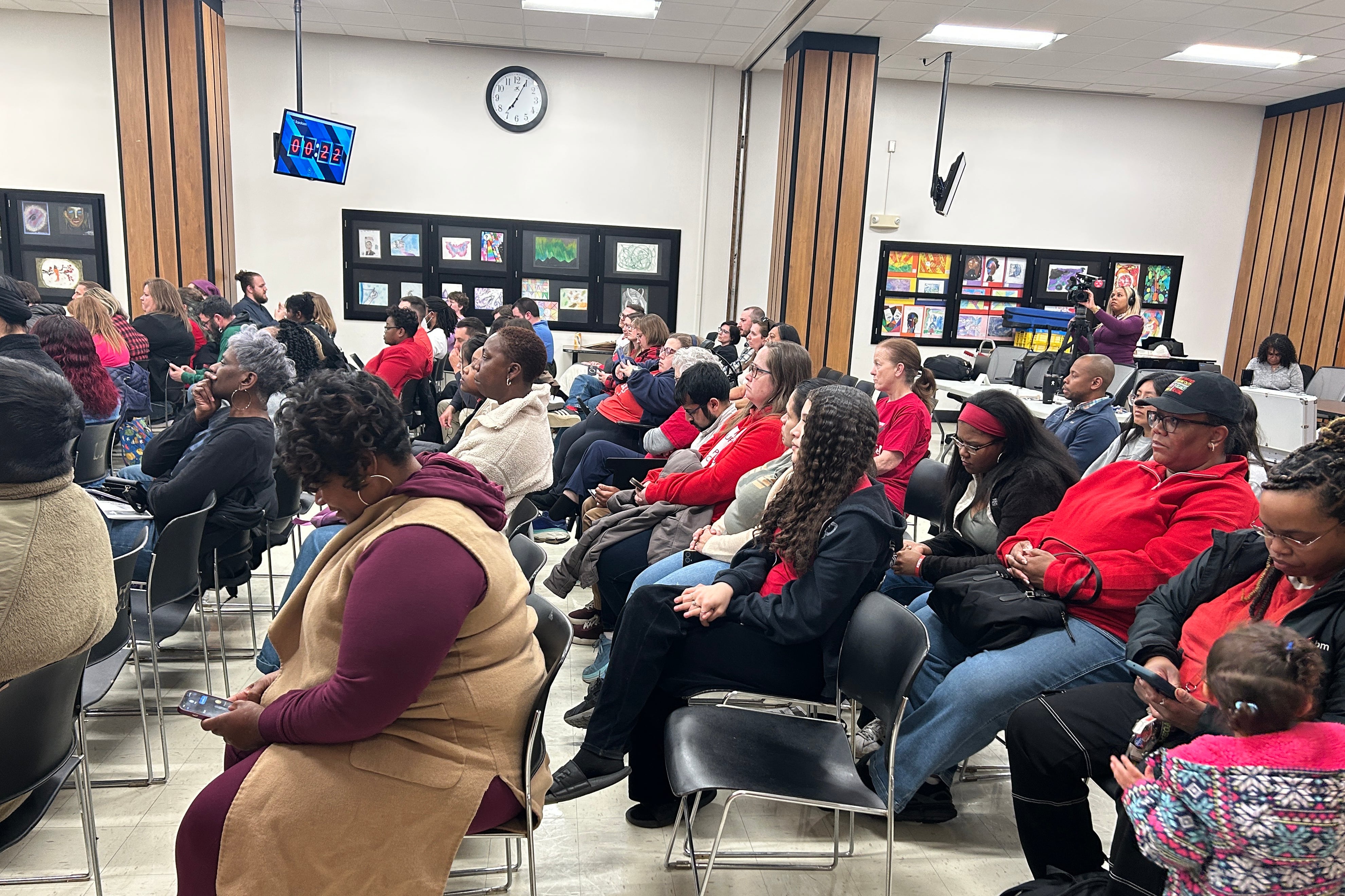 A group of people sit in rows of chairs in a conference room.