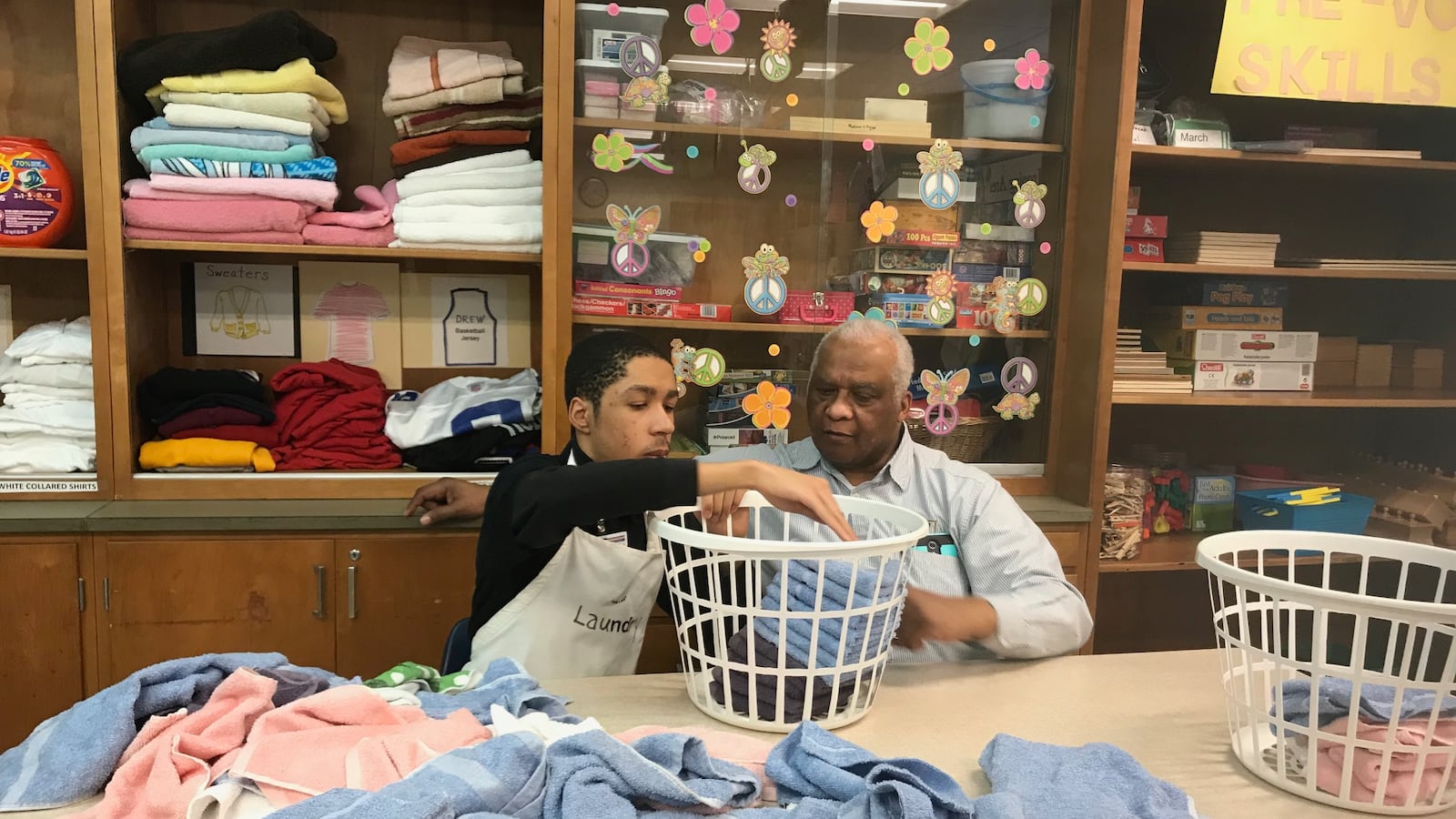 A Charles R. Drew Transition Center student practices folding laundry as his teacher looks on at the special education school in Detroit
