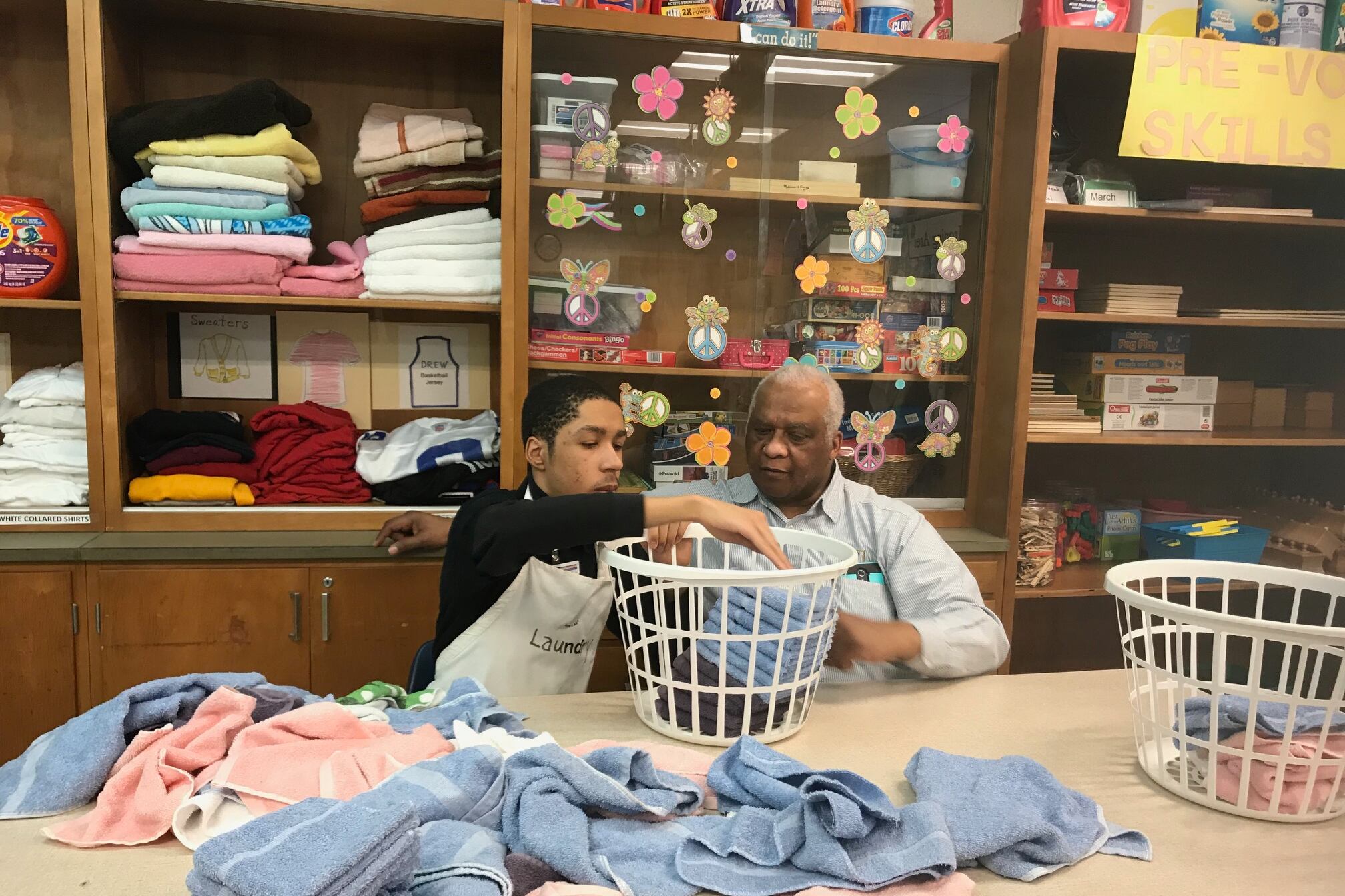 A Charles R. Drew Transition Center student practices folding laundry as his teacher looks on at the special education school in Detroit