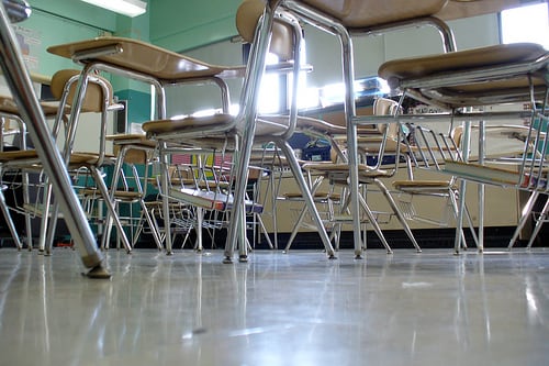 A classroom with green walls and empty desks.