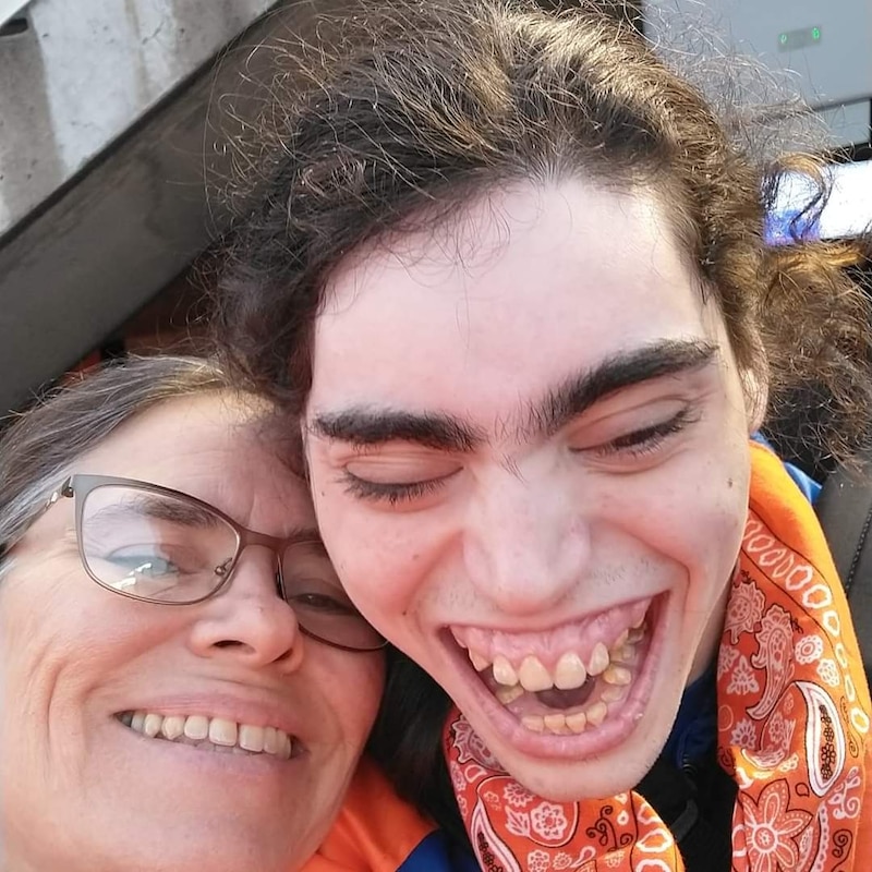 A smiling woman and her smiling son. Both mom and son have dark hair.