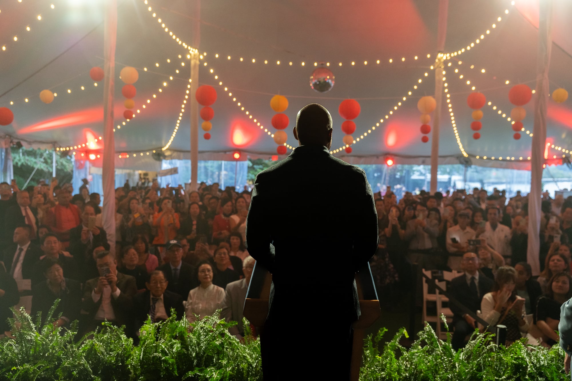A man in a suit with his back to the camera looks out on a crowd.