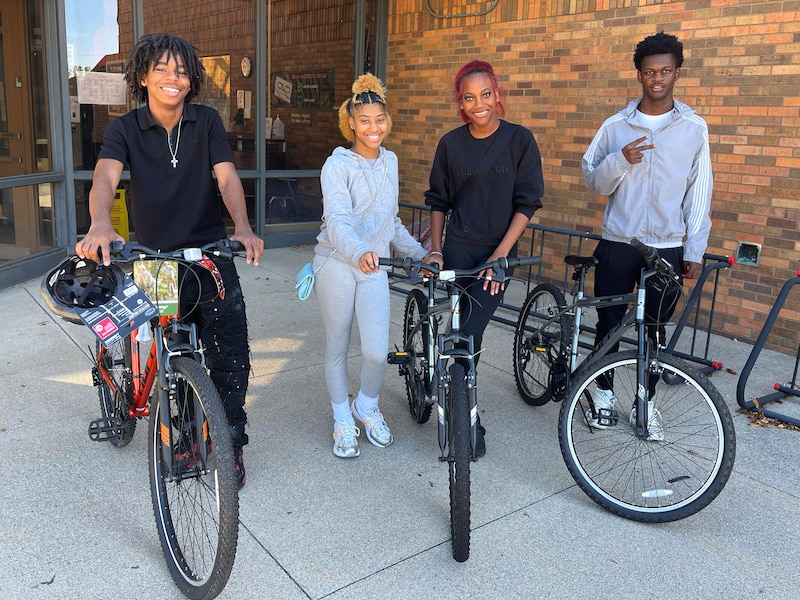 Four students stand with bikes.