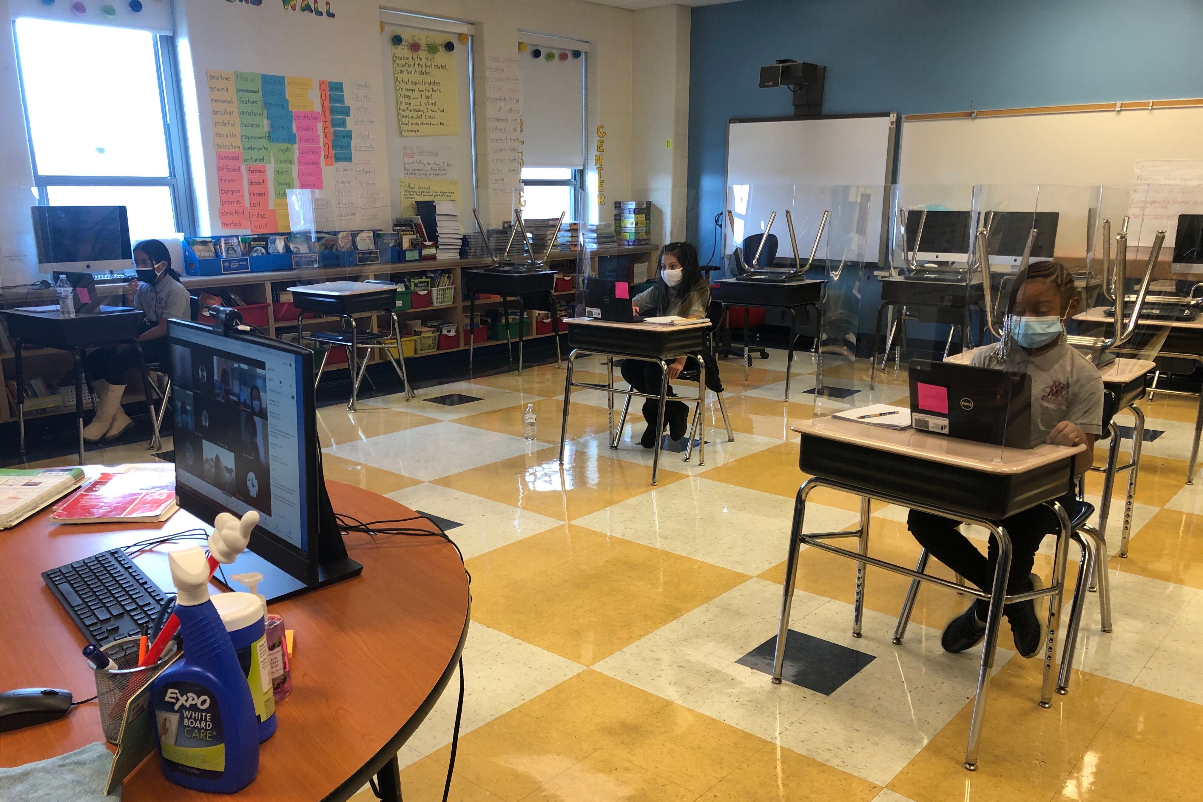 At Miles Davis Magnet Academy in Chicago, a teacher juggles simultaneous instruction in a classroom where some fourth graders are learning in person and others are learning remotely.