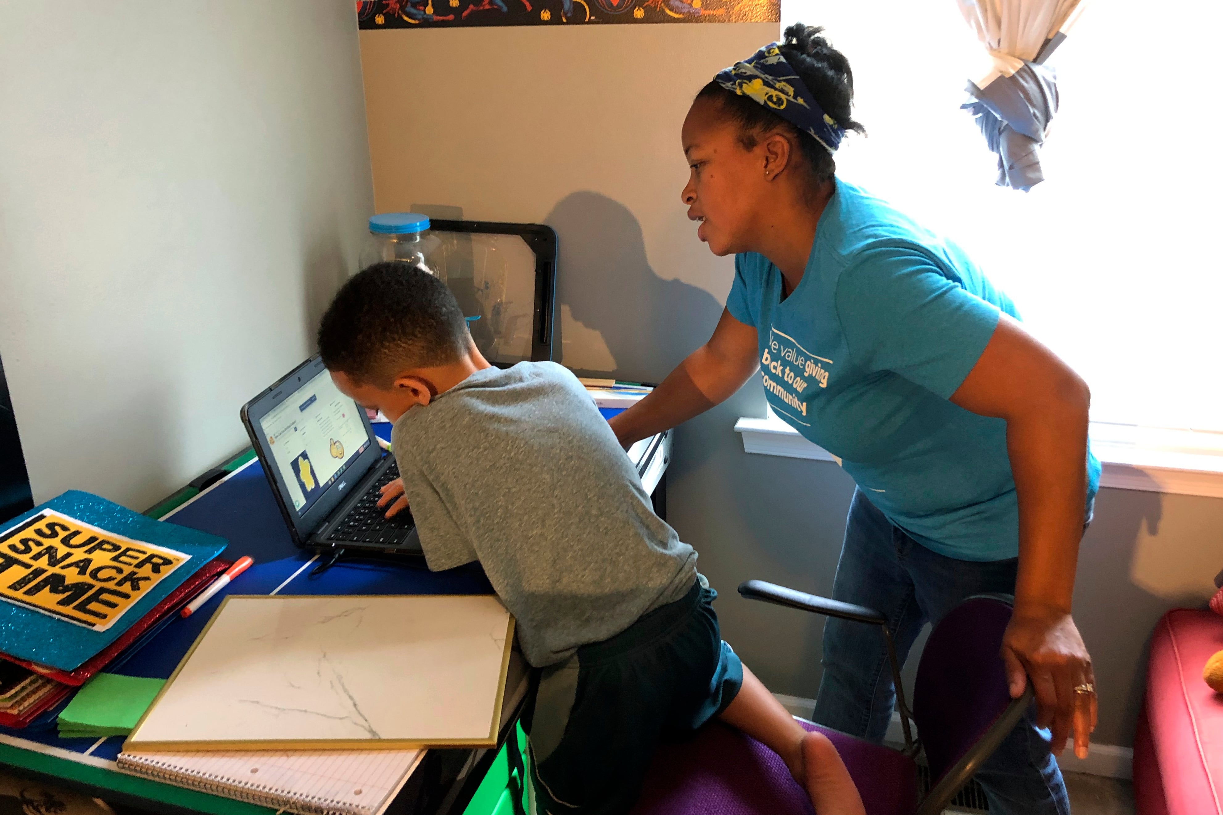 Tiffany Shelton helps her 7-year-old son, P.J. Shelton, a second grader, during an online class at their home in Norristown, Pa