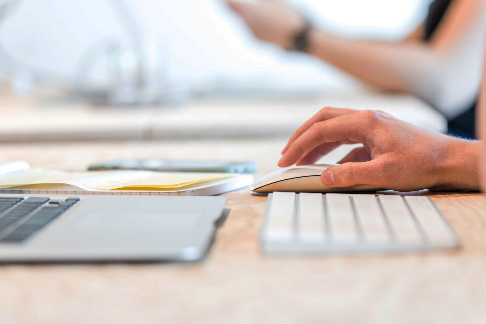 Close up of a hand on a computer mouse next to a keyboard.