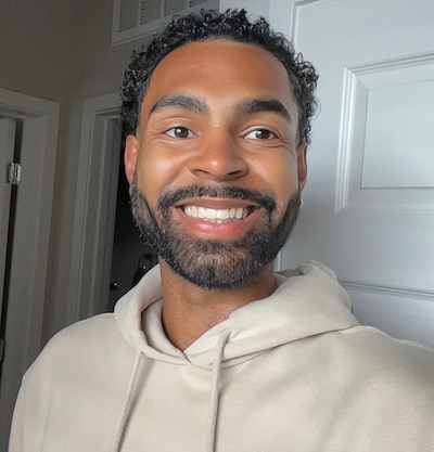 Headshot of a smiling man with an off-white sweatshirt.